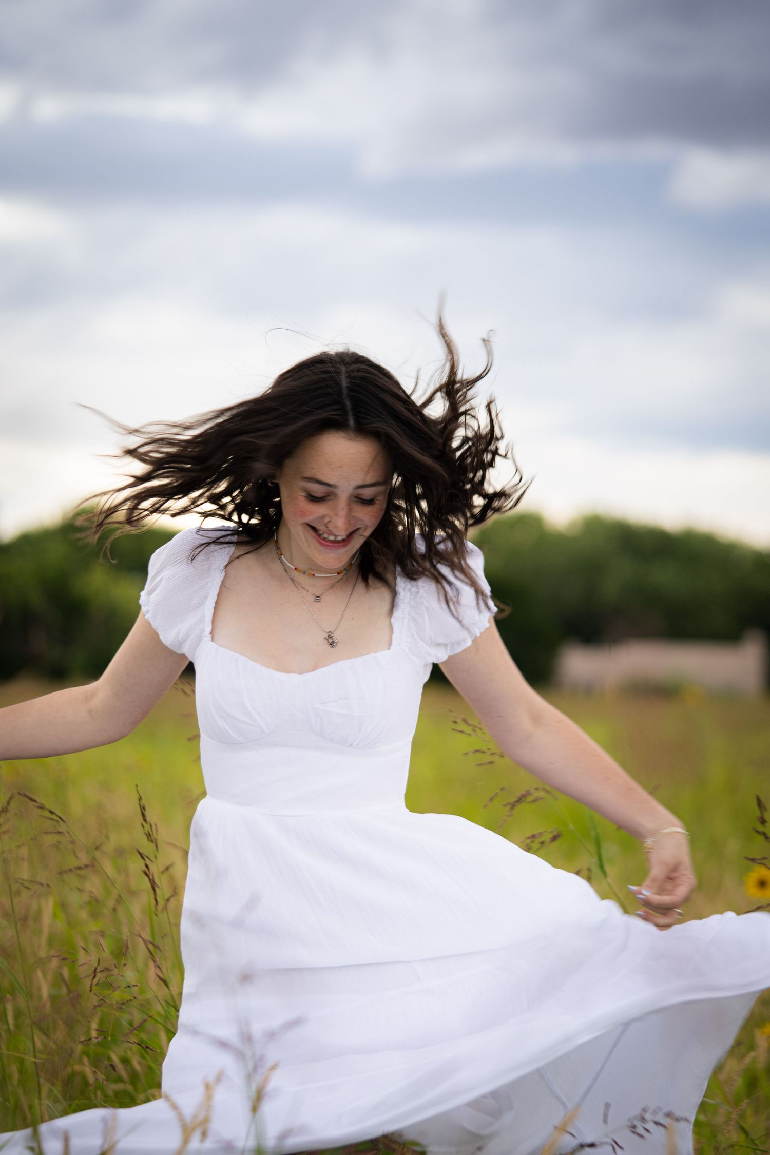 Figure in flowing white dress twirls joyfully in a summer field.