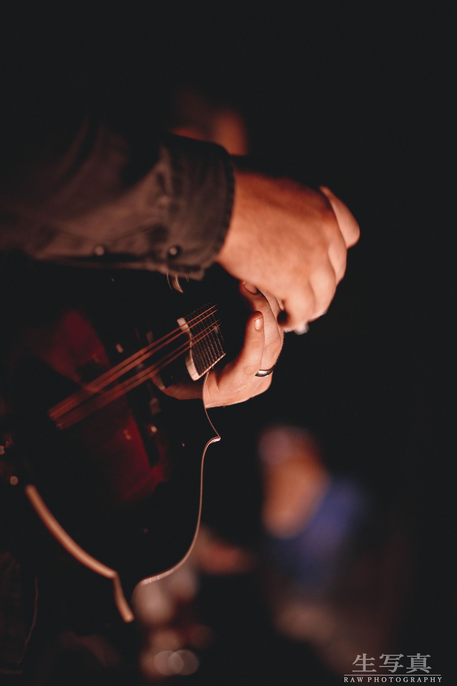 Close-up shots of hands playing stringed instrument in dark concert lighting.