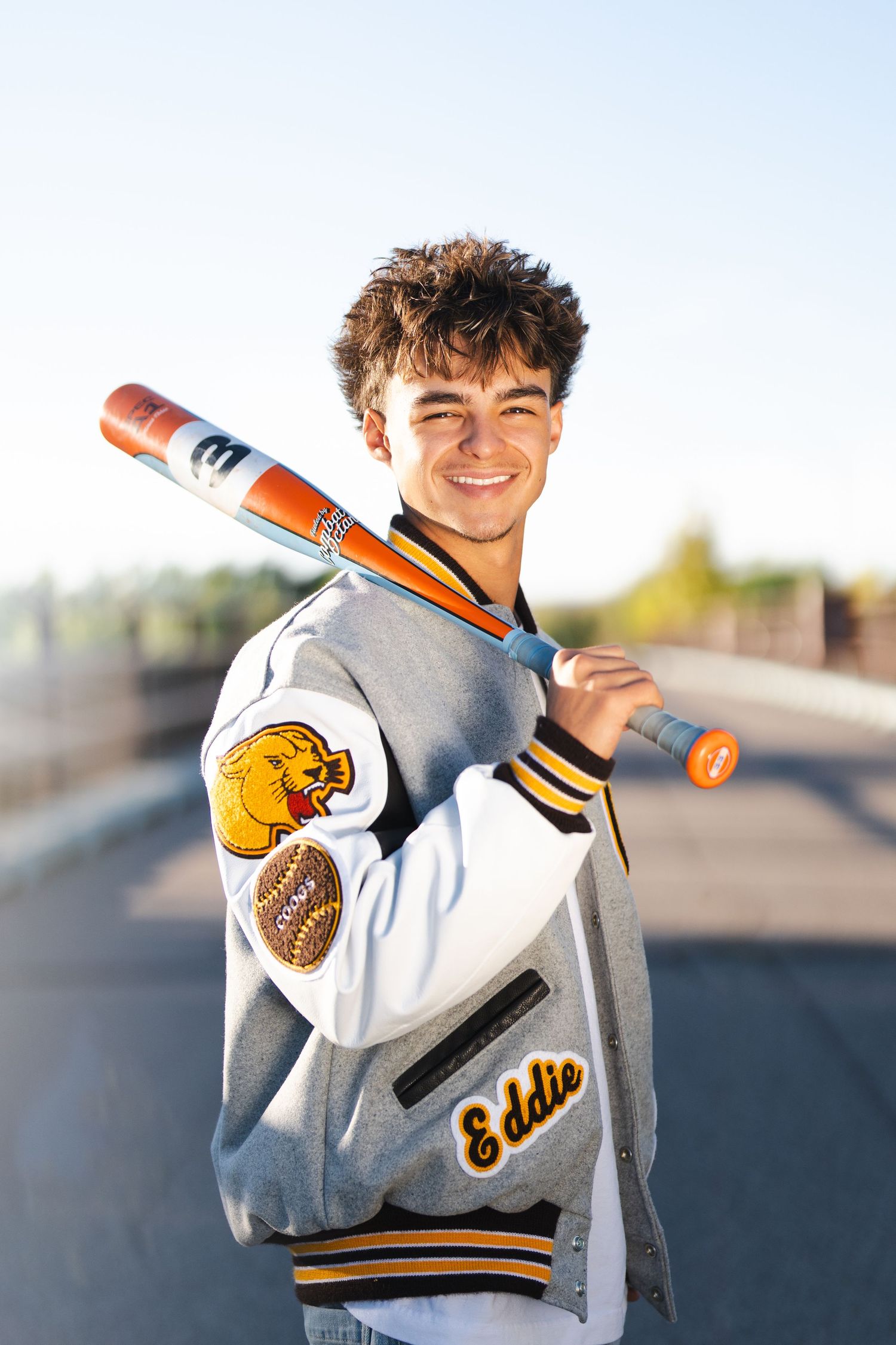 Grey and yellow varsity jacket with mascot patch and athletic details.