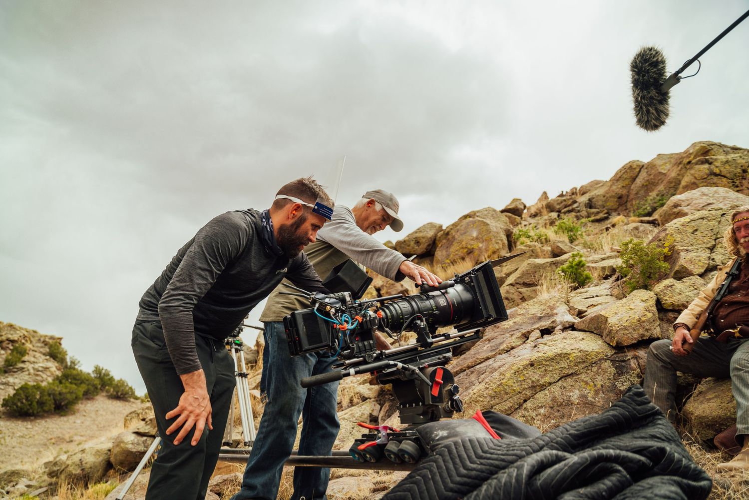 Camera operators filming on rocky terrain with professional equipment.