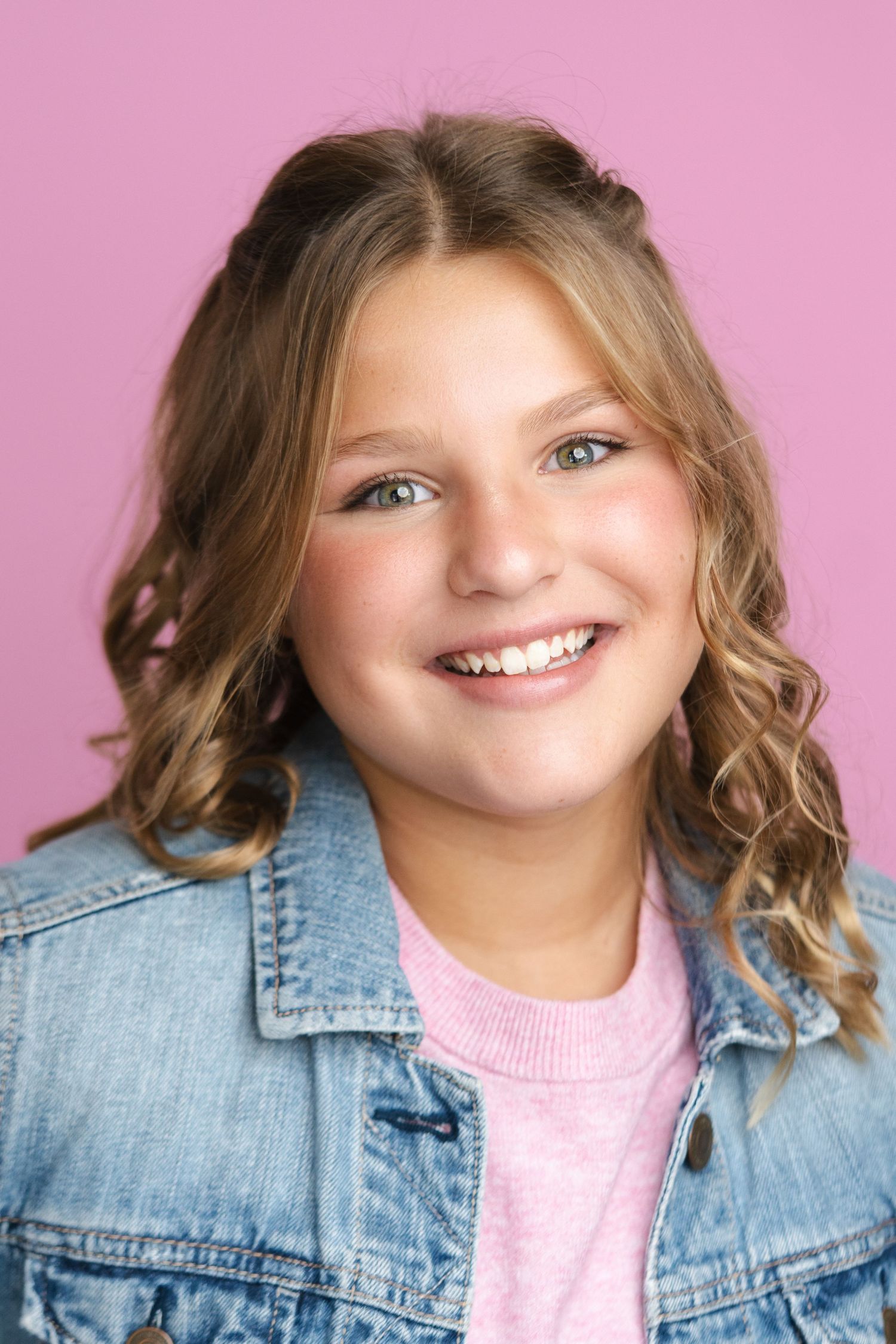 Casual portrait series in denim jacket and pink top against pink background.