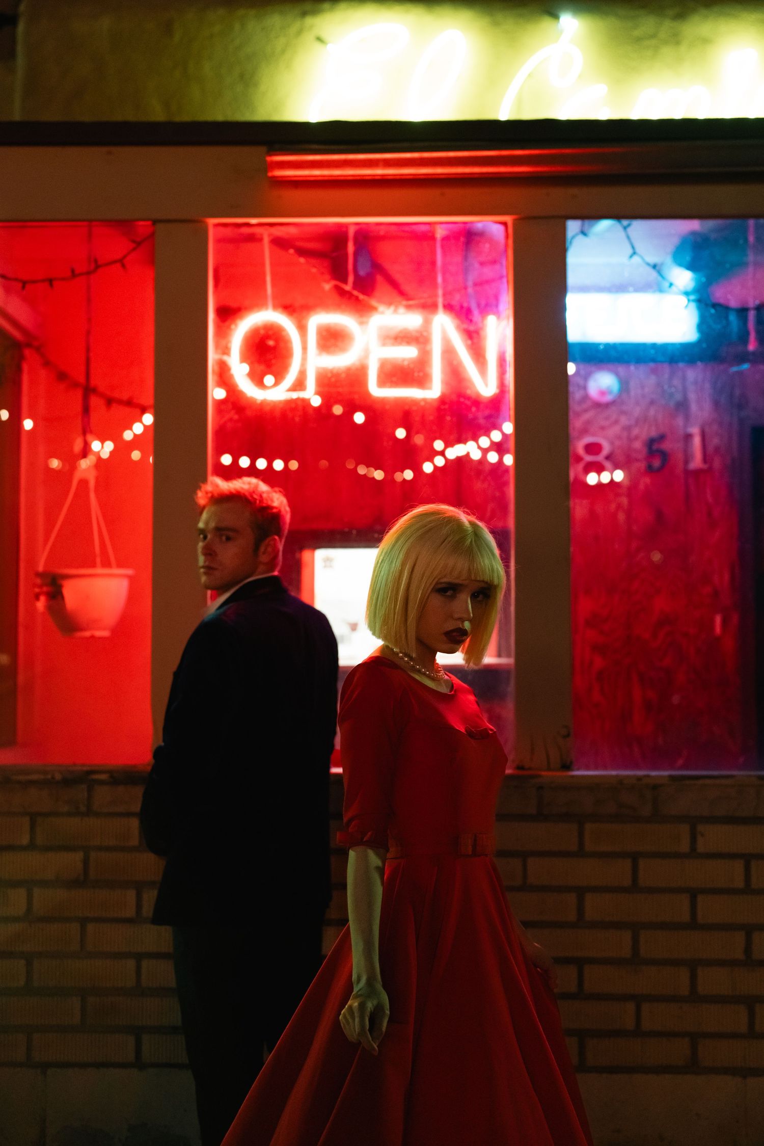 Dramatic nighttime scene with neon open sign and red lighting in storefront window.