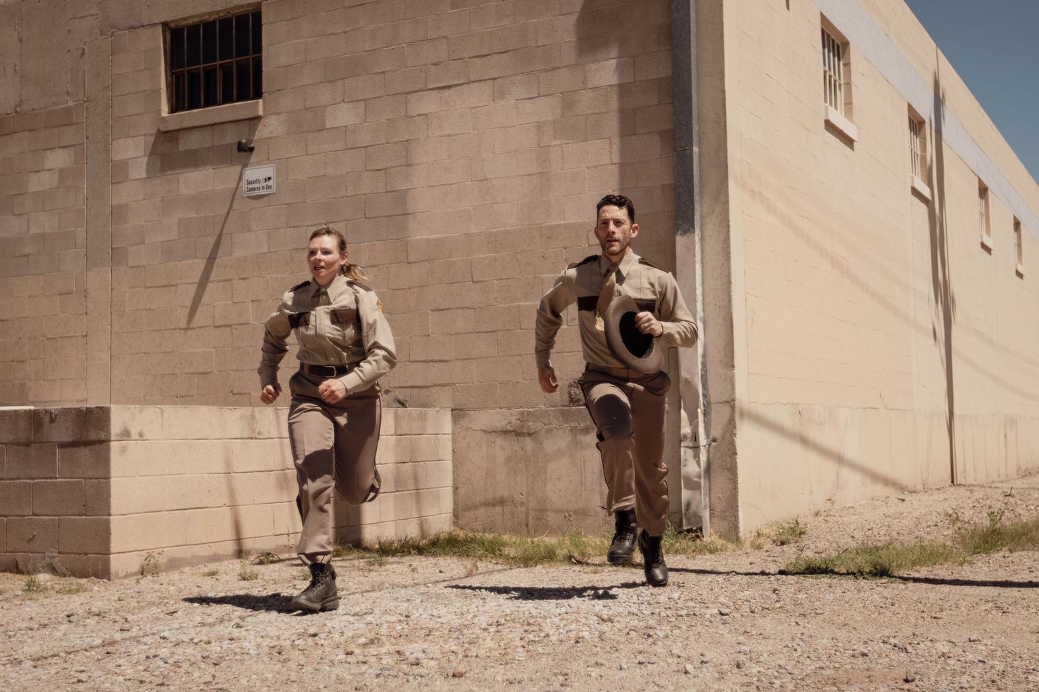 Action sequence filmed along concrete building exterior.