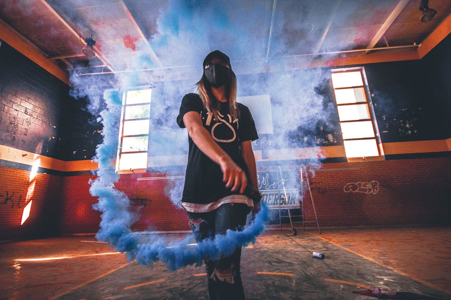 Dramatic concert scene with red and blue smoke effects on stage during a live performance.