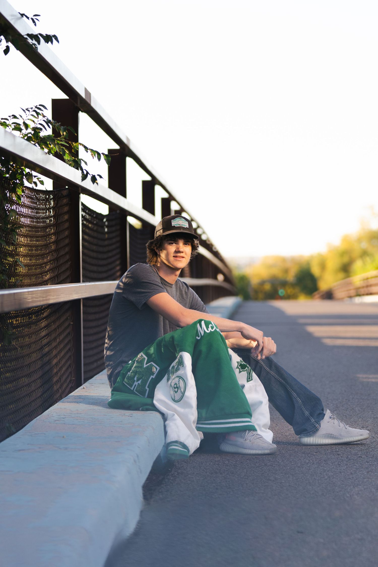 A person in casual attire sits on a concrete surface during golden hour.