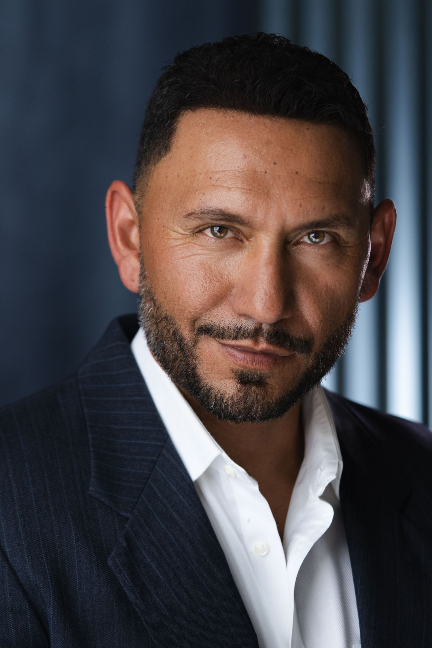 Professional portrait series showing different angles in white shirt and pinstripe suit.