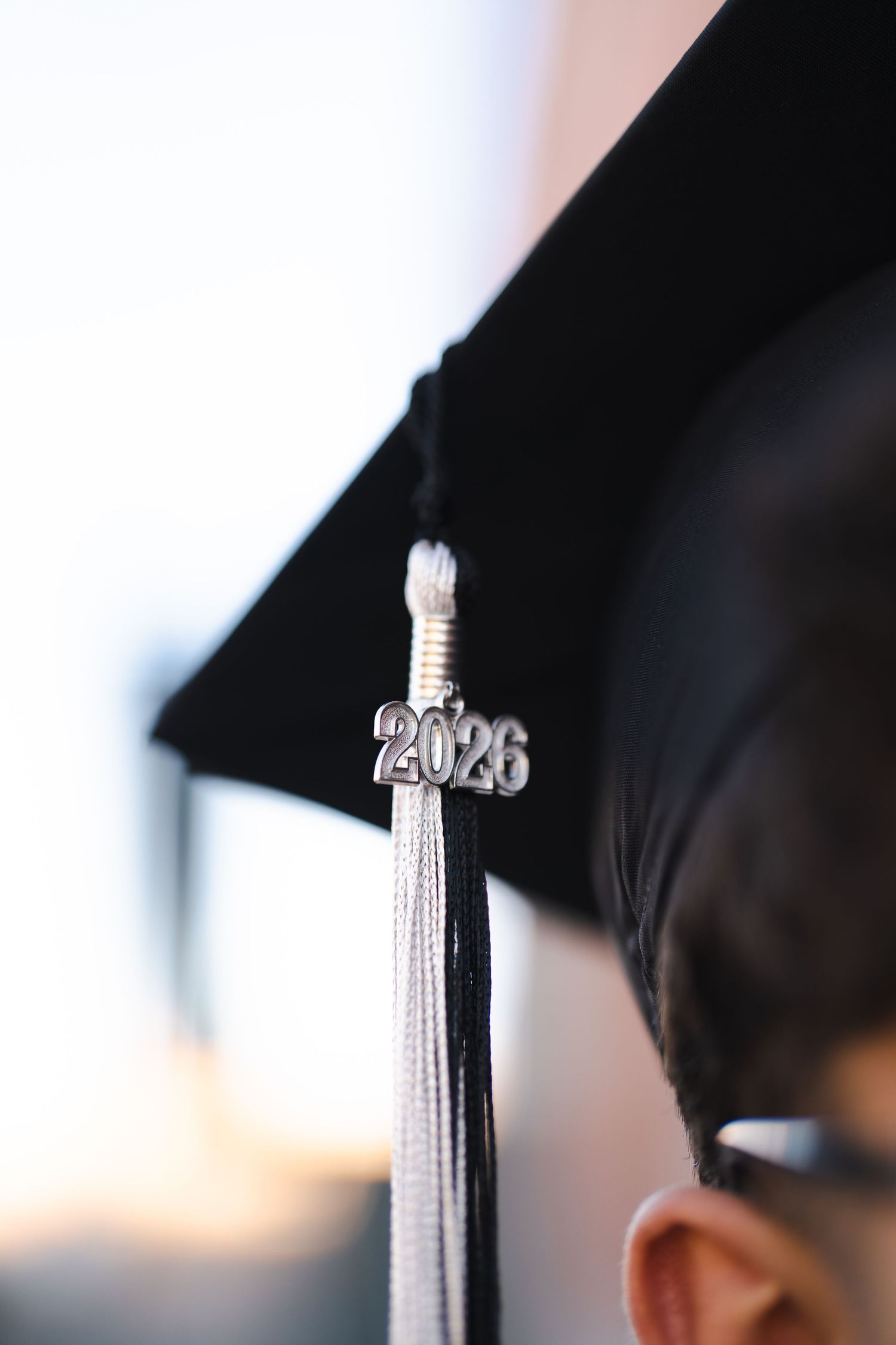Graduation tassel detail with 2020 charm hanging from a black cap.