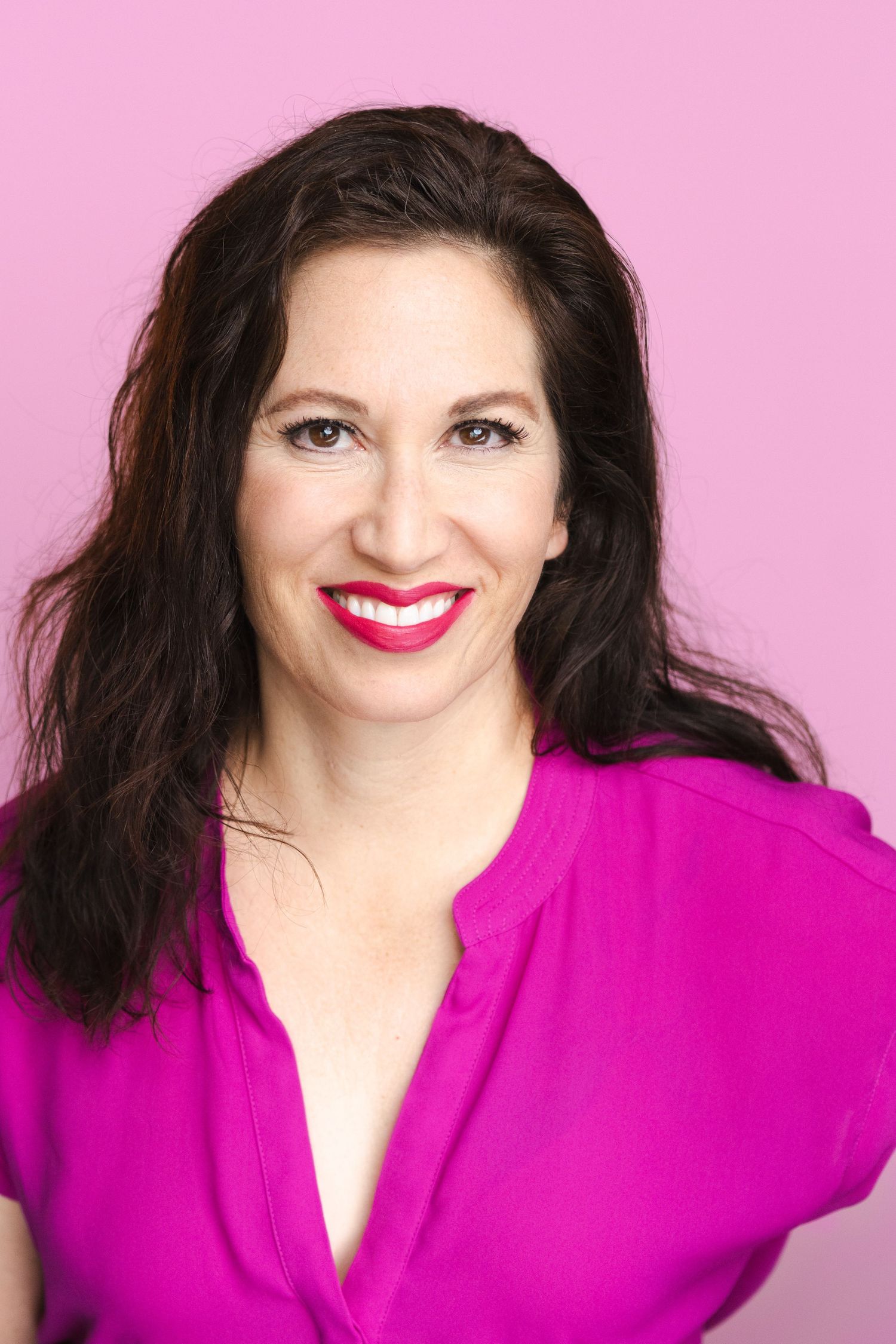 Vibrant portrait of person in magenta top against pink background.