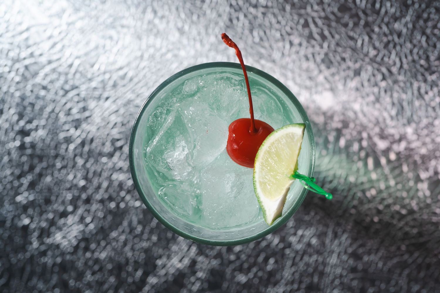 Classic margarita with lime and cherry garnish in a textured glass.