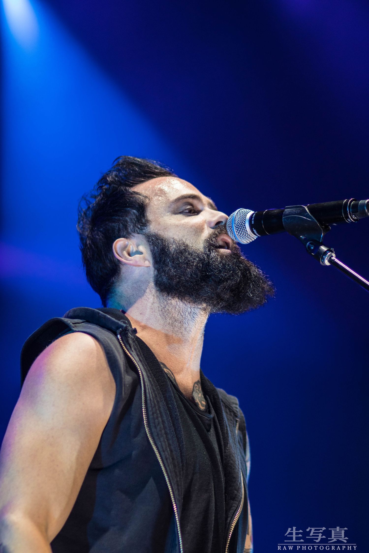 Singer performing passionately with microphone against vibrant blue stage lighting.