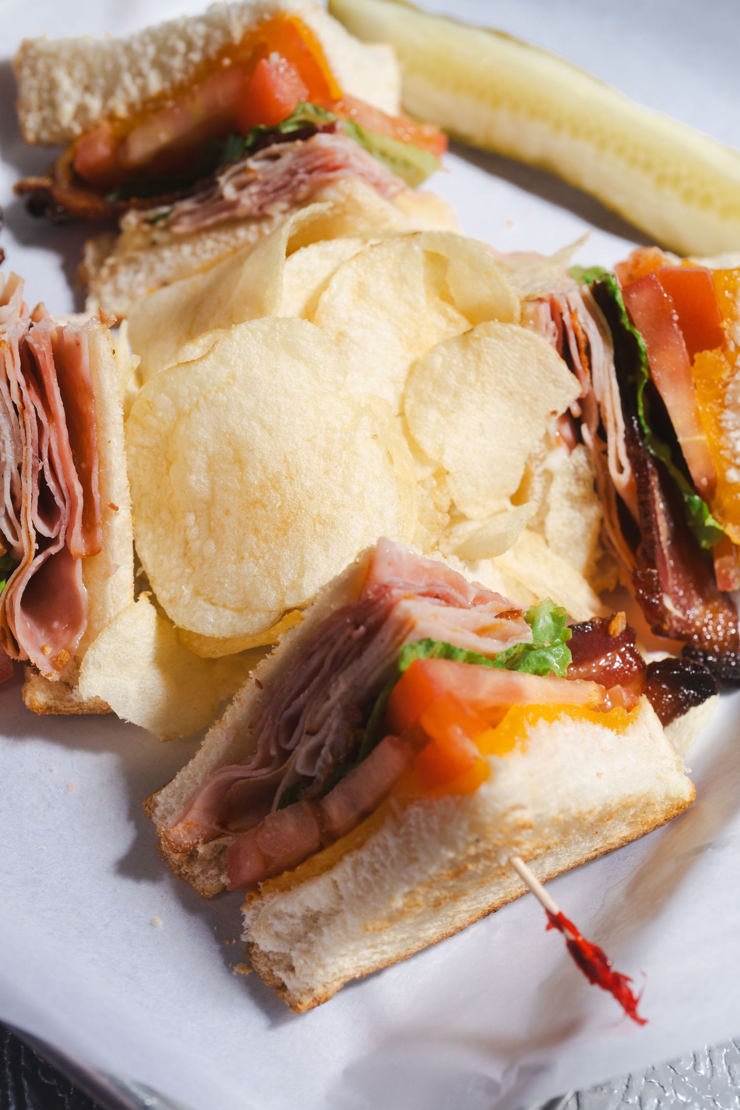 Sliced deli sandwich on crusty bread with layers of meat, cheese, and vegetables.