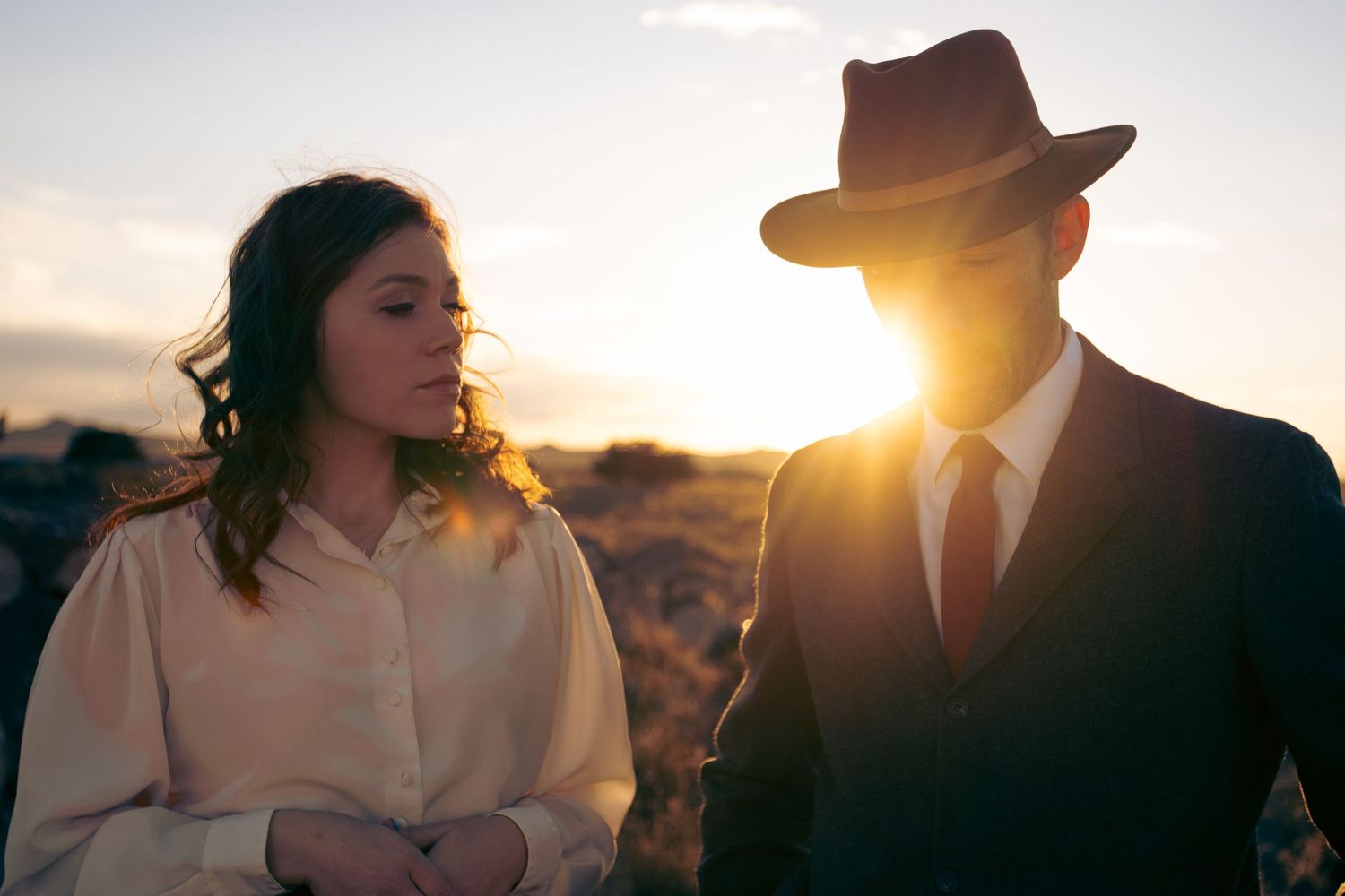 Silhouettes of people against dramatic sunset in desert landscape.