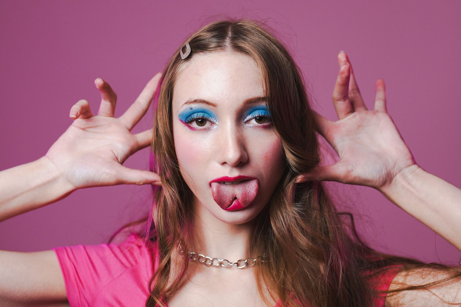 Playful portrait series with bright makeup and expressive poses against pink backdrop.