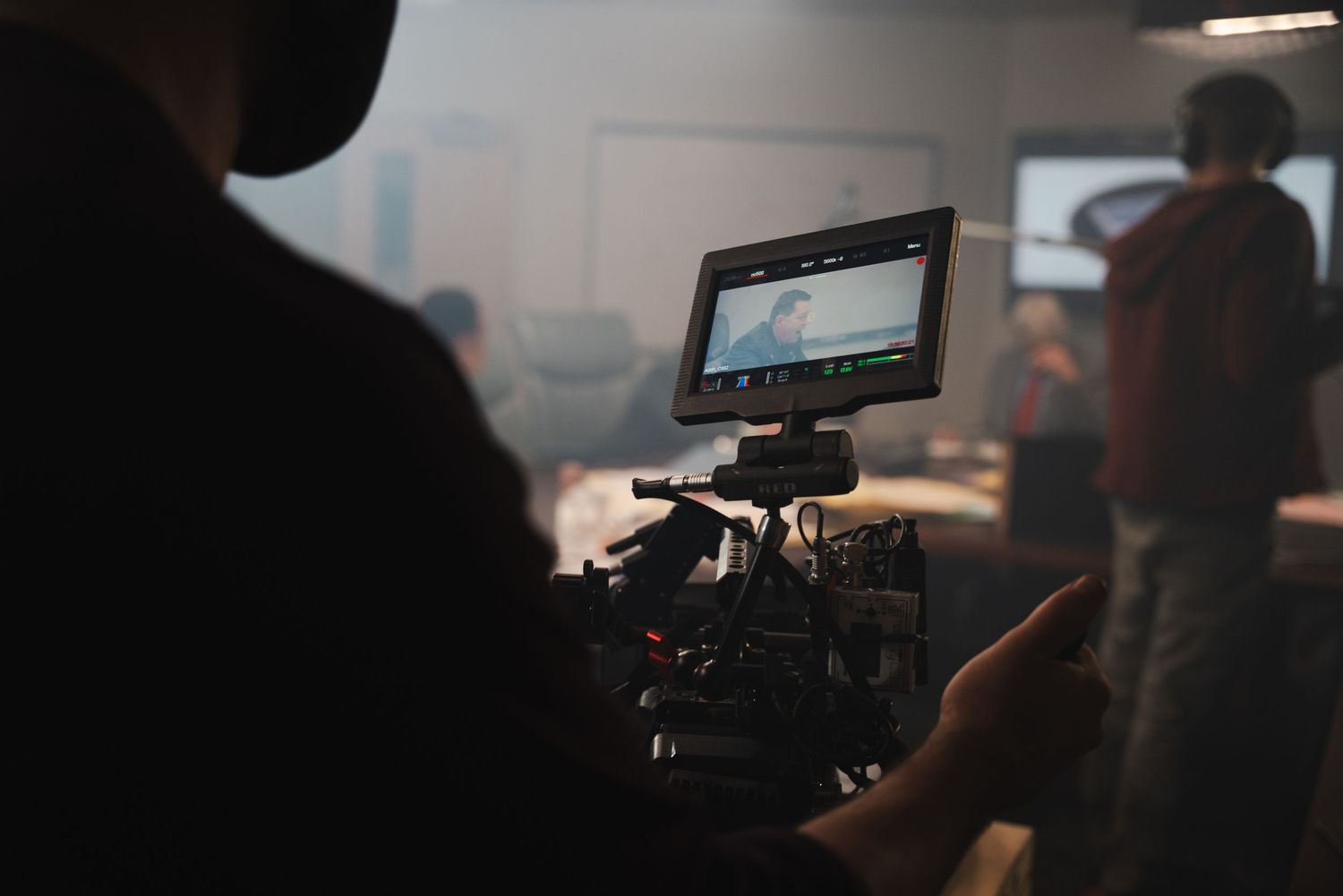 Professional video production equipment and cameras silhouetted against dark background.