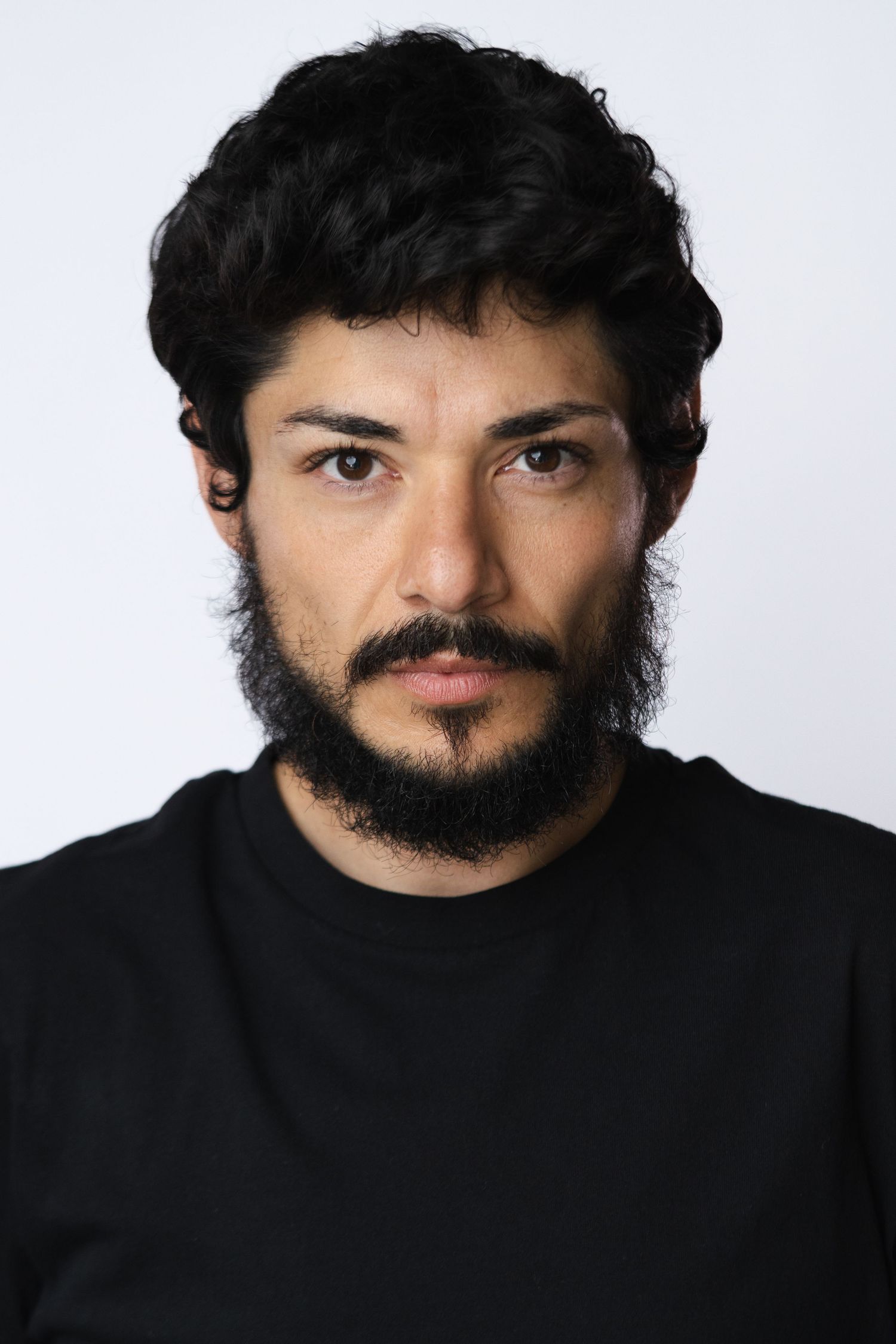 Dramatic portrait series in black turtleneck showing intense gaze against white background.