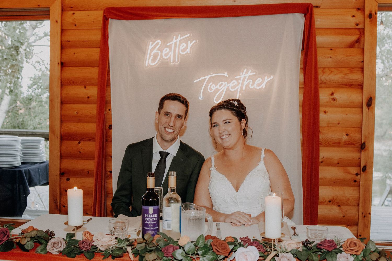 Wedding reception decor in rustic log cabin with red accent wall and projection screen.