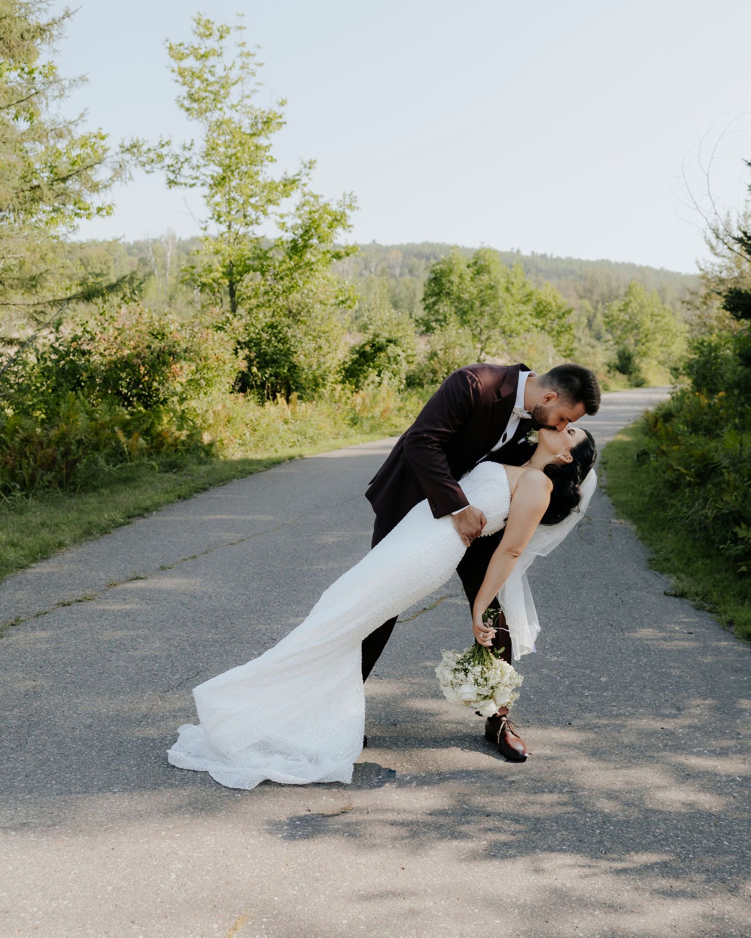 Romantic dip pose on pathway with couple in wedding attire.