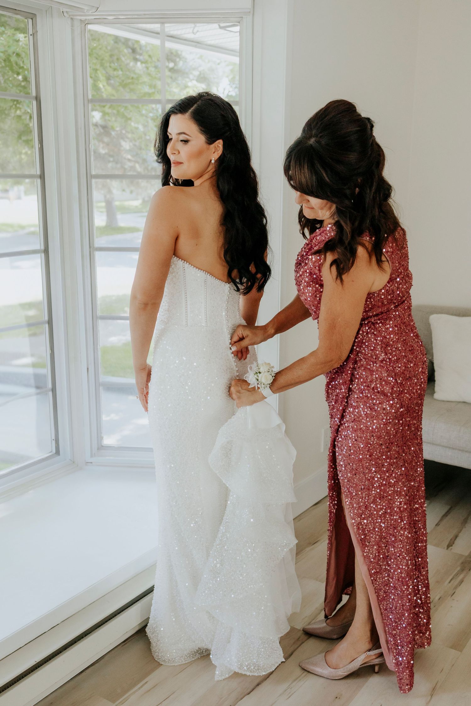 Wedding dress fitting session with sparkly red bridesmaid dress in bright modern room.