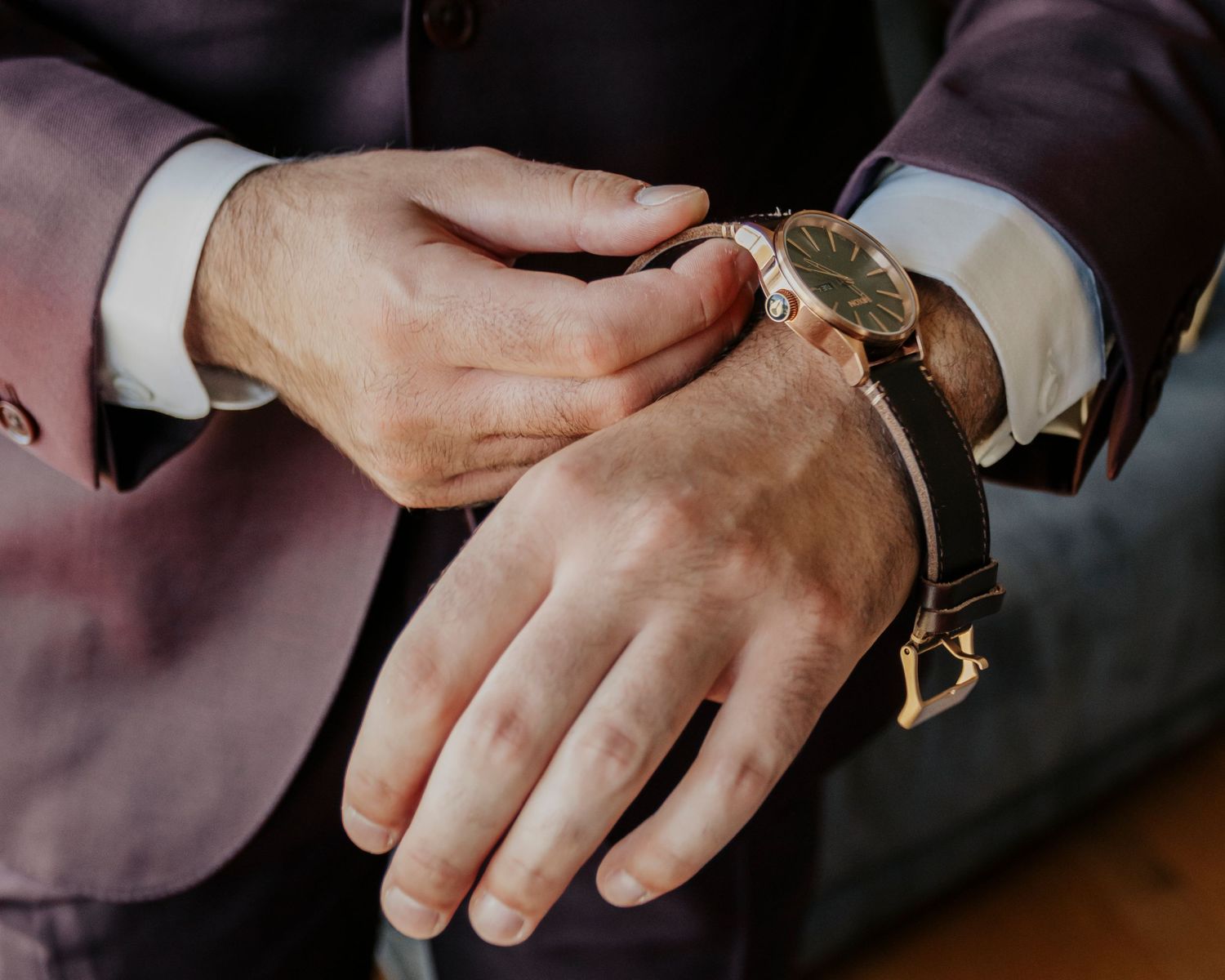 Close-up shot of hands adjusting a watch band against a dark background.