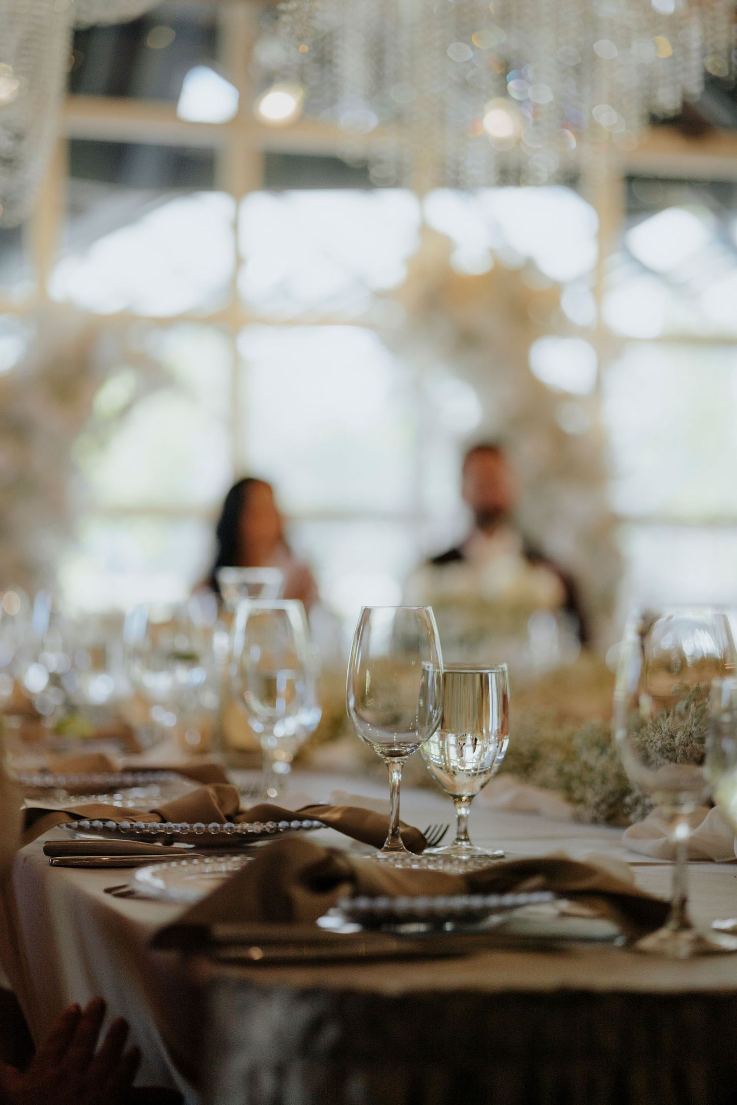 Elegant wedding reception table settings with wine glasses and soft lighting.