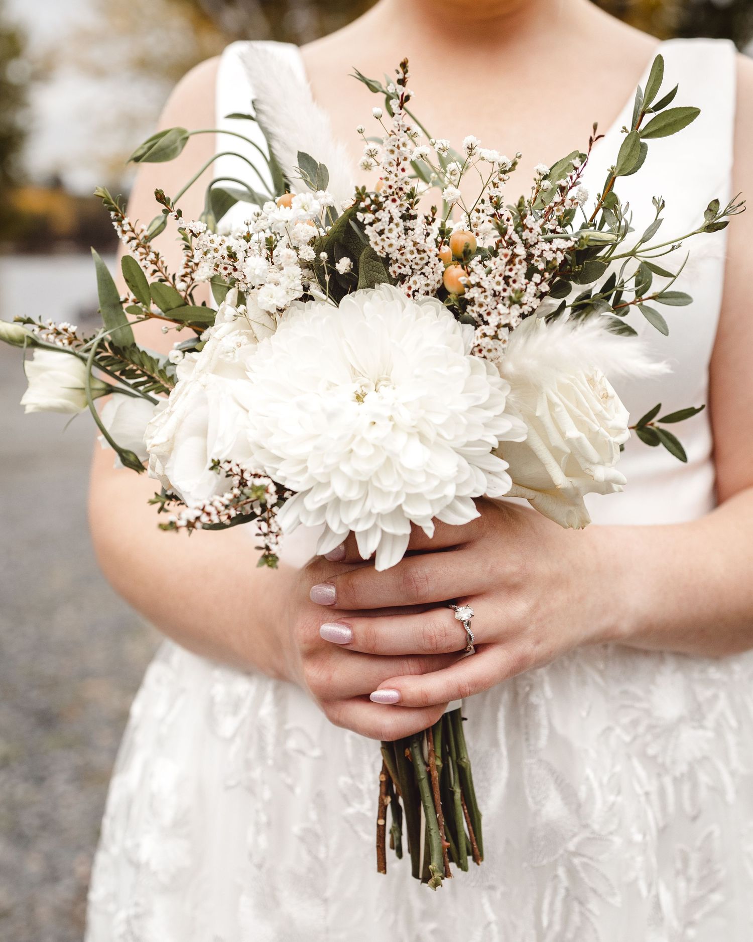 An elegant white wedding bouquet with peonies, greenery, and delicate wildflowers.