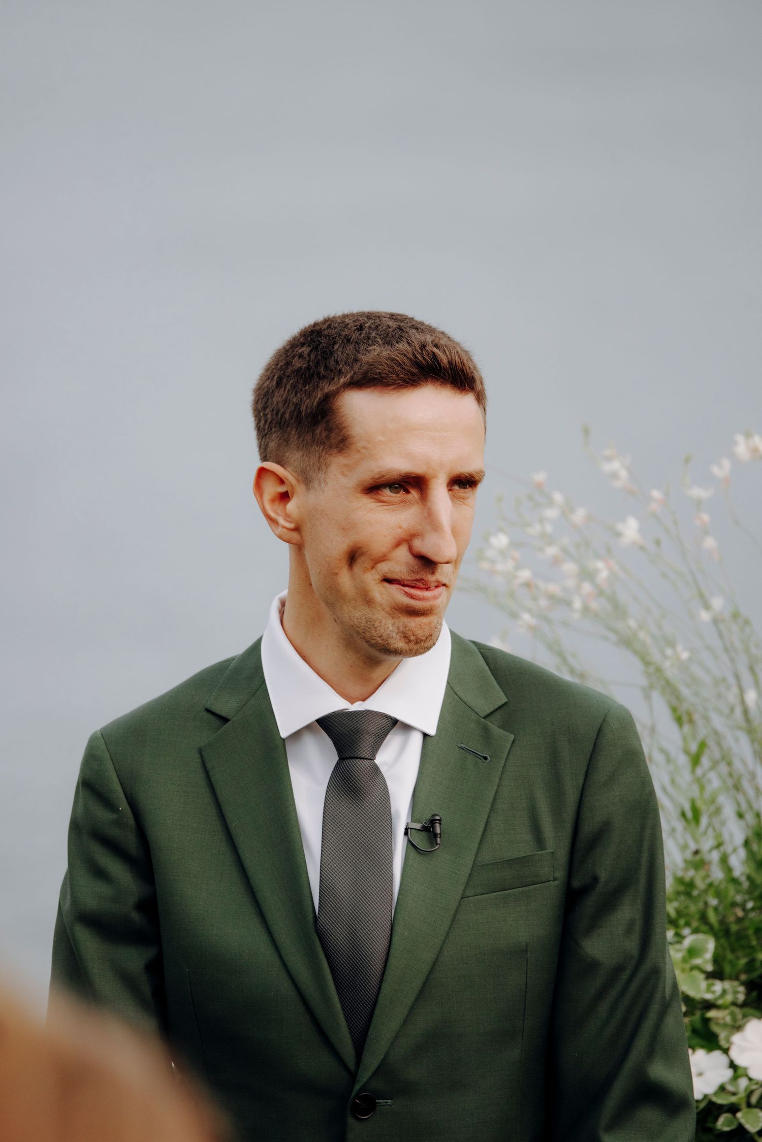 Close-up shot of groom in dark green suit and grey tie.
