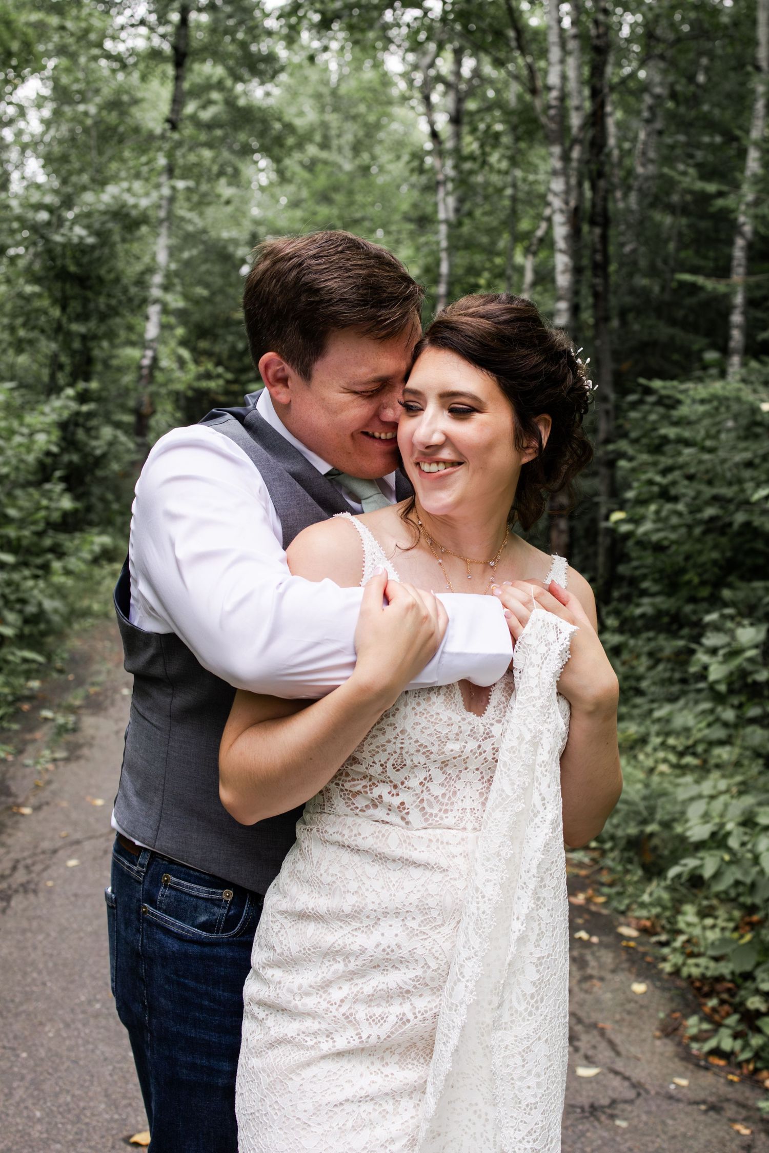 Candid wedding moment captured in a wooded outdoor setting.