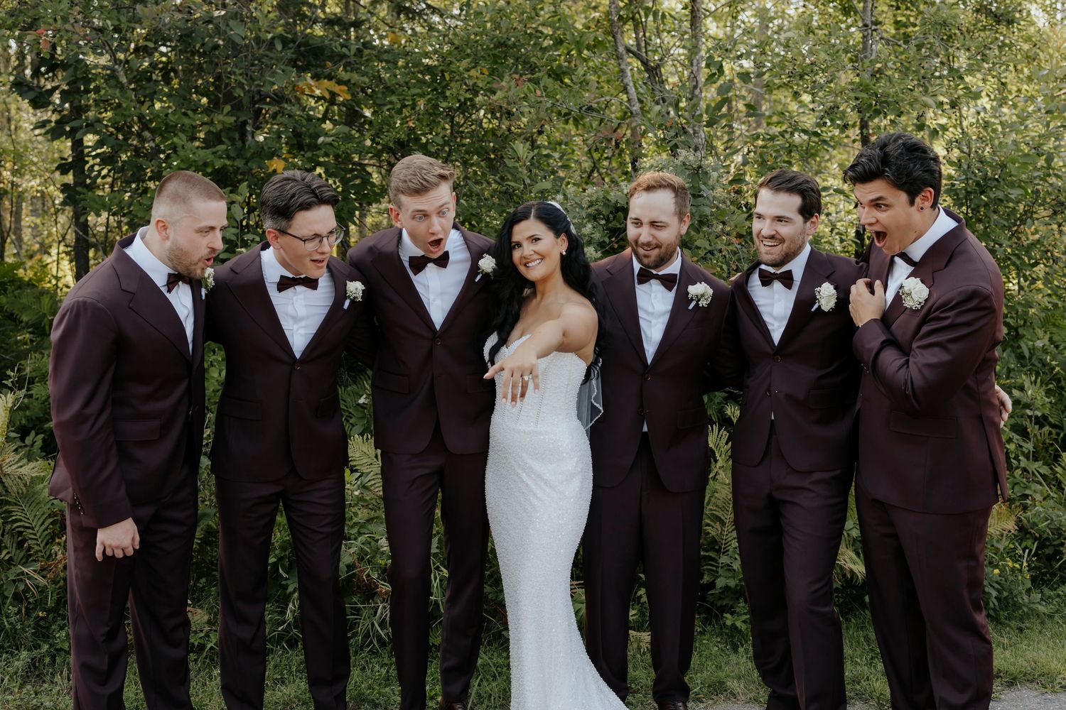 Wedding party in brown suits and white dress posing outdoors.