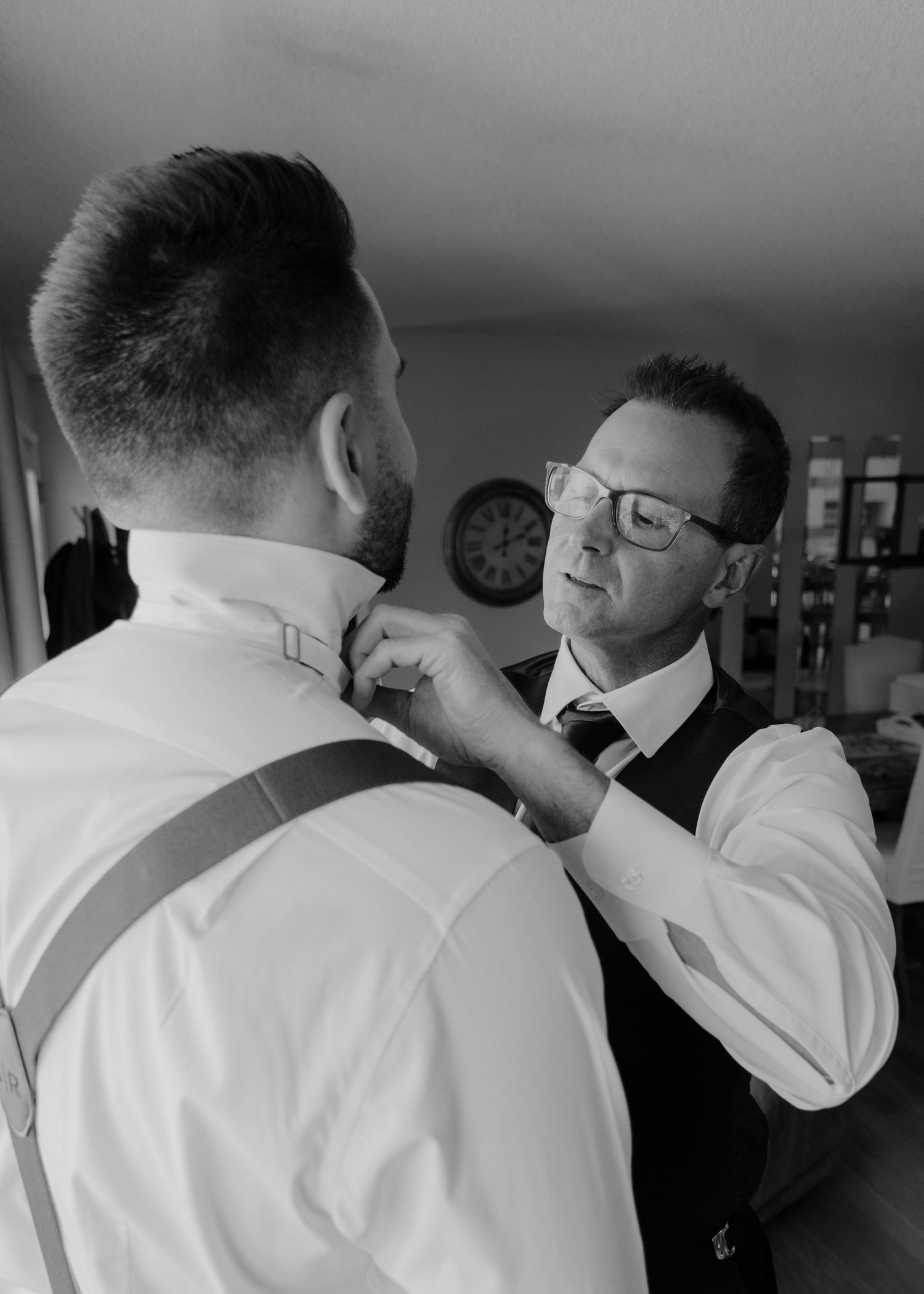 Men in white dress shirts adjusting ties and preparing for formal event.