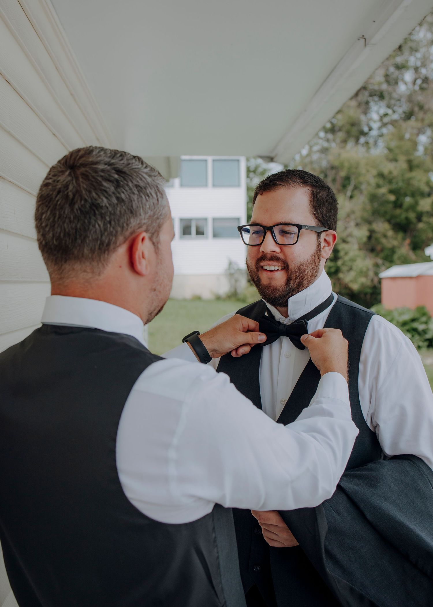A sequence of photos showing someone helping adjust a black bowtie on another person in formal attire.