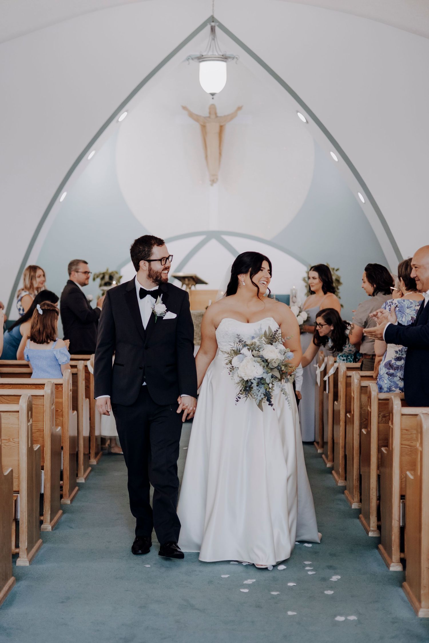 Wedding guests and bridal party gathered in a church aisle after the ceremony.