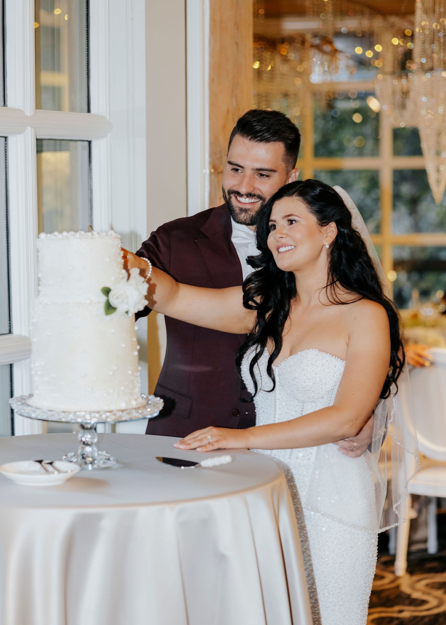 Couple cuts their elegant white wedding cake at their reception.