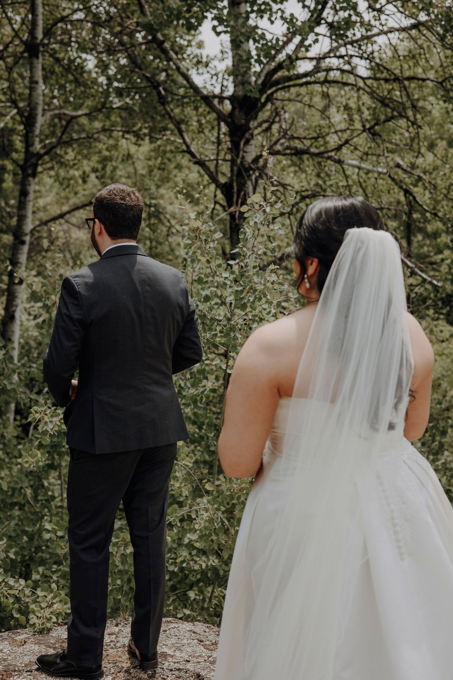 Artistic series of wedding photos showing couple from behind walking through lush green forest setting.