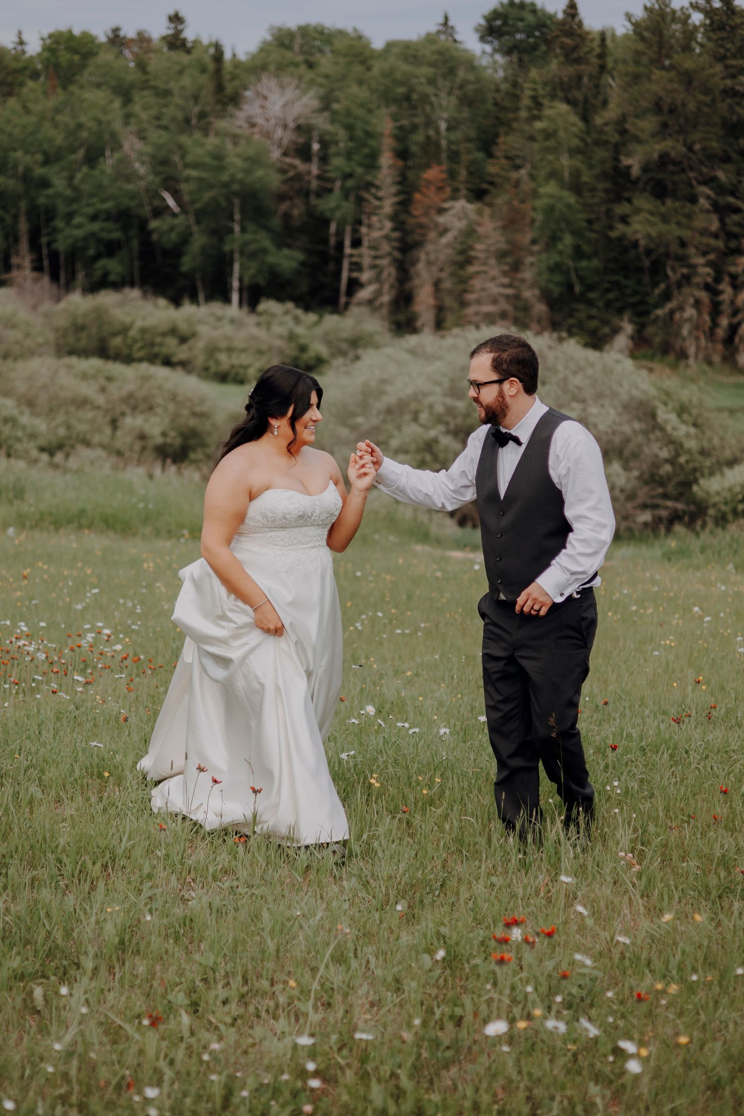 A couple dances playfully in a wildflower meadow during their wedding photoshoot.