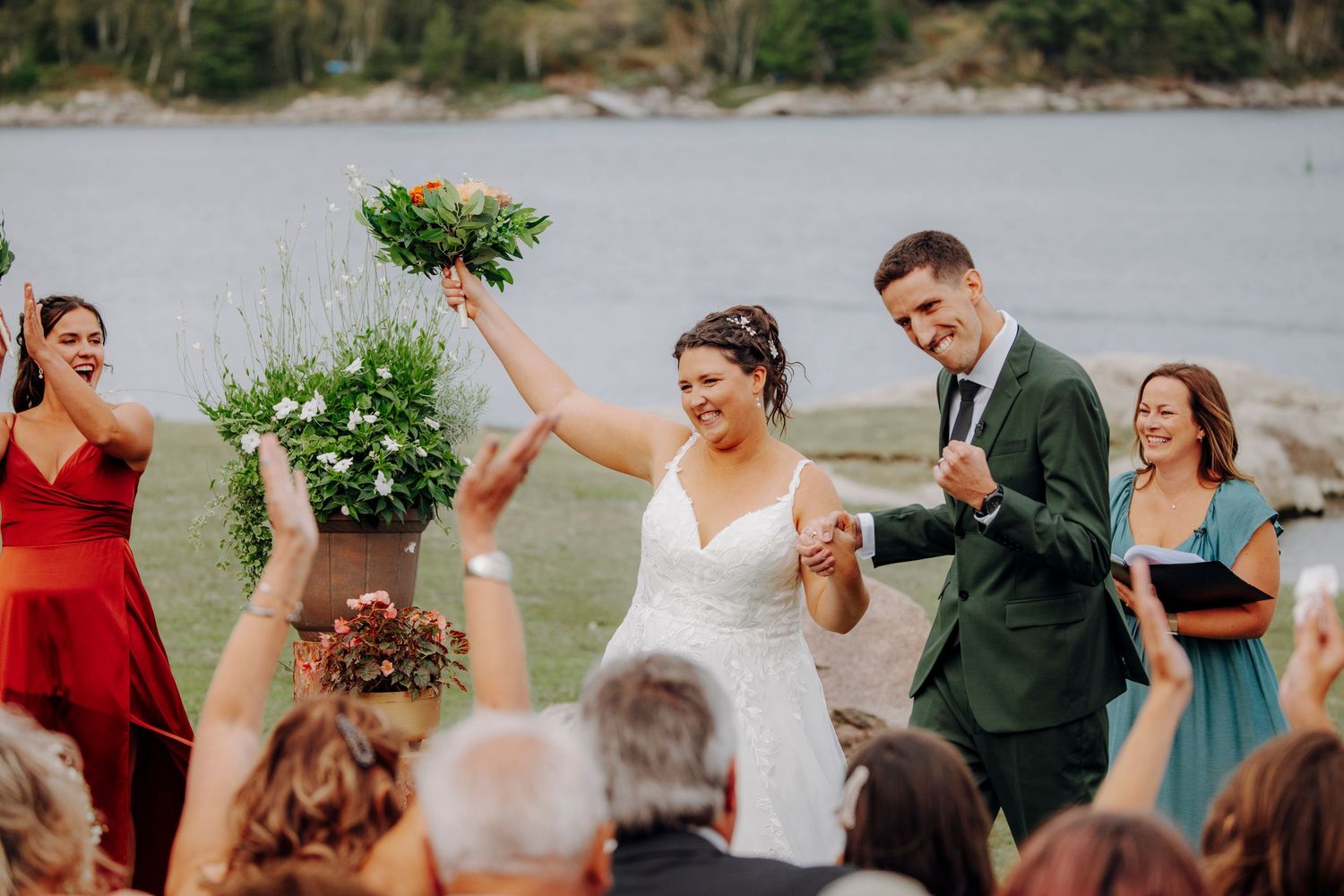Wedding party celebrates outdoors with decorative wooden posts and floral arrangements.