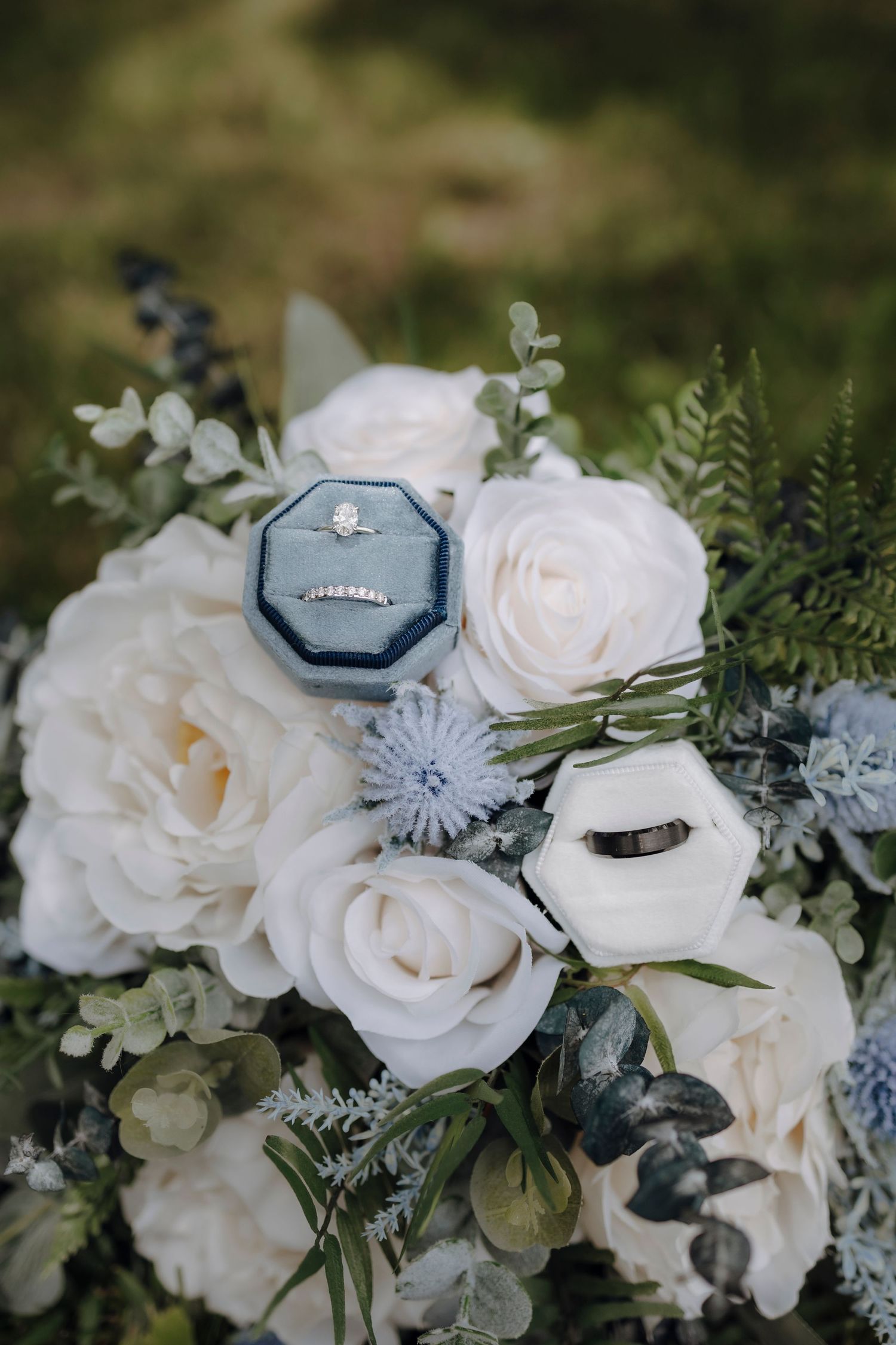 White roses and delicate floral arrangements with a wedding ring box nestled among the blooms.