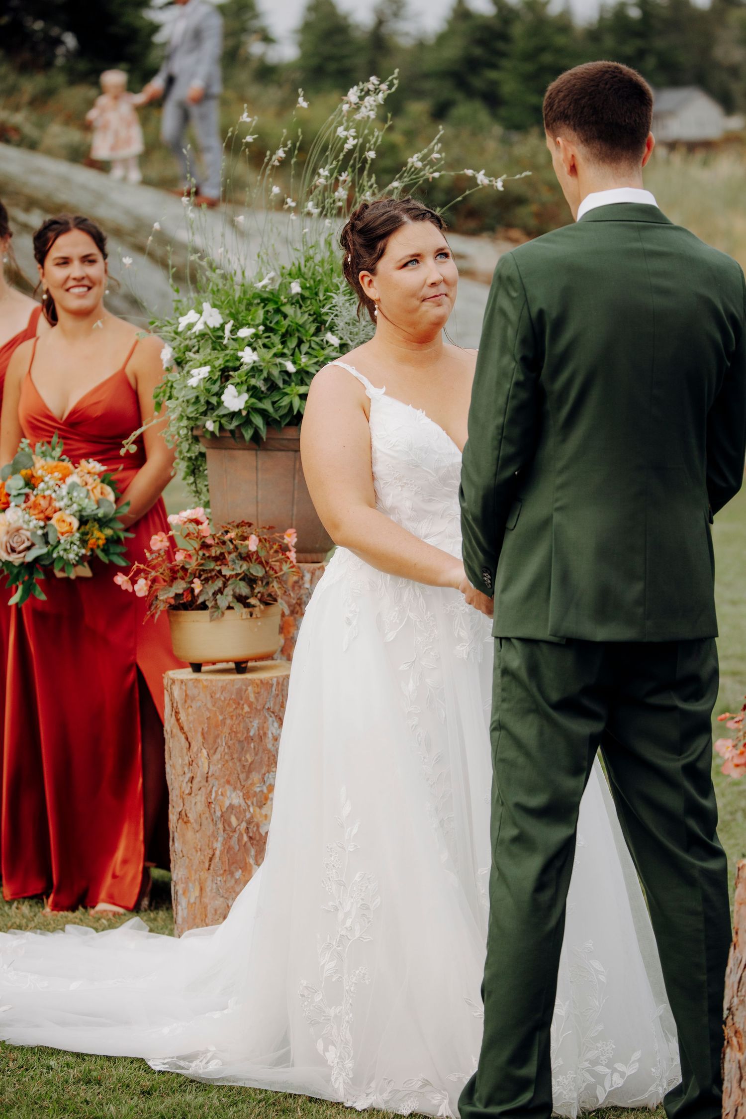 Wedding party arranged outdoors with bridesmaids in burgundy dresses holding vibrant bouquets.