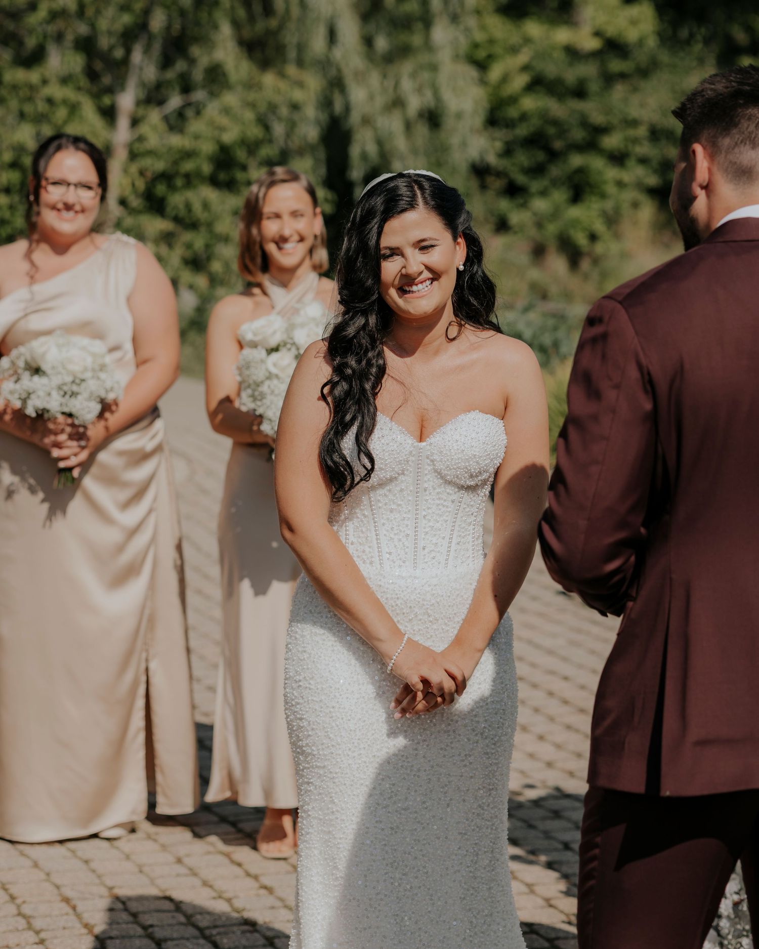 A wedding party poses outdoors in burgundy and champagne colored attire.
