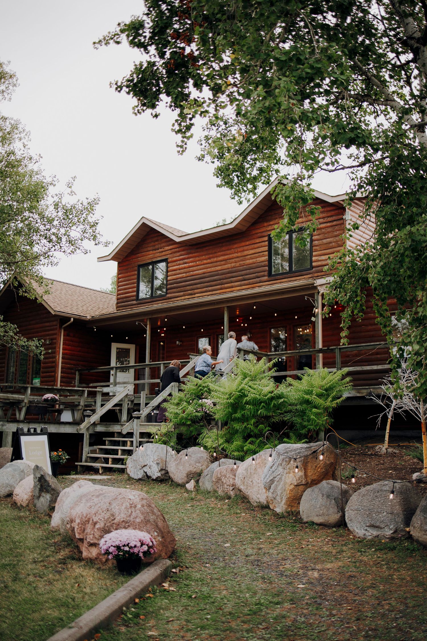 Rustic log cabin lodge with large boulders landscaping the front yard.