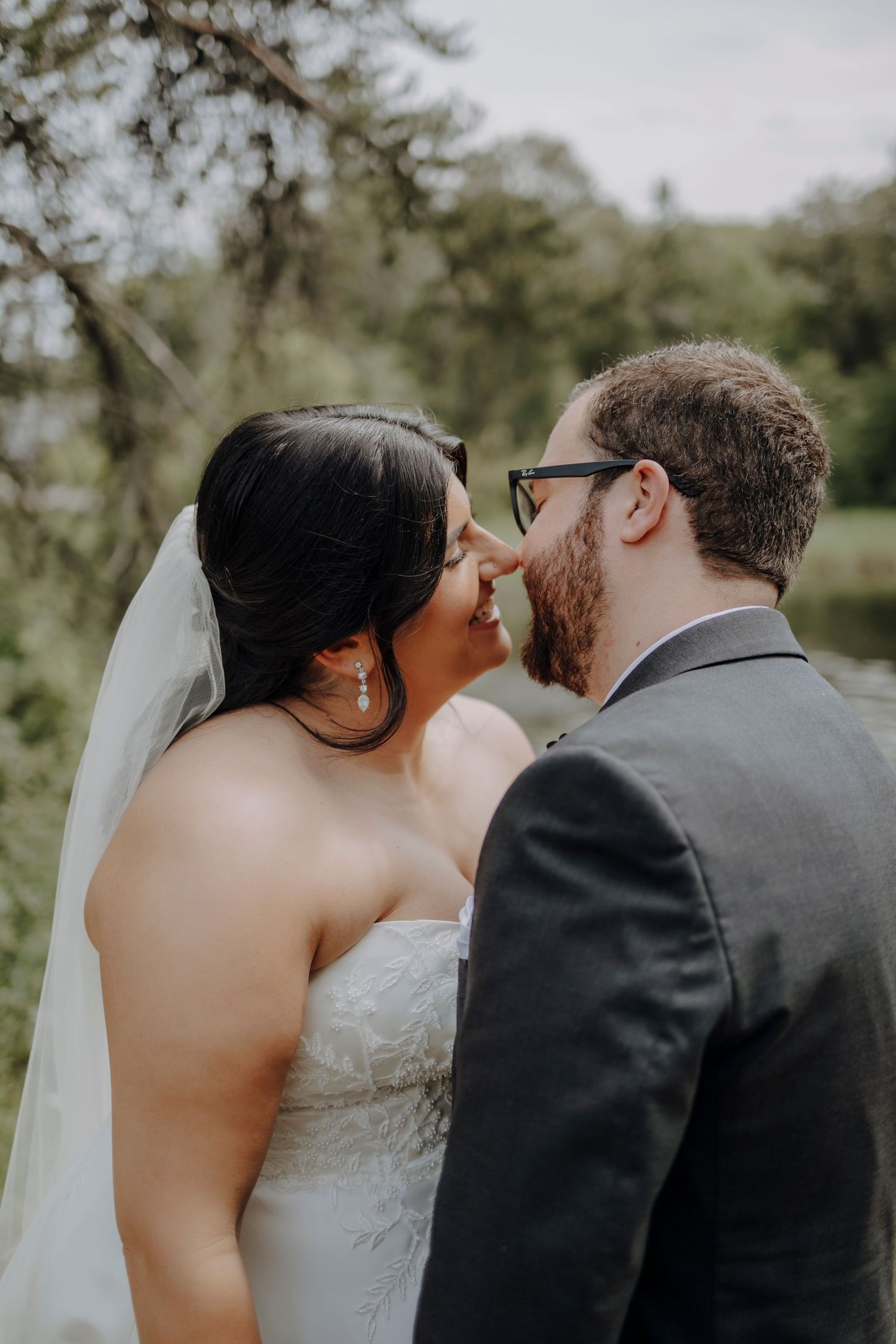 Wedding couple shares intimate moment outdoors with bride wearing white dress and veil.