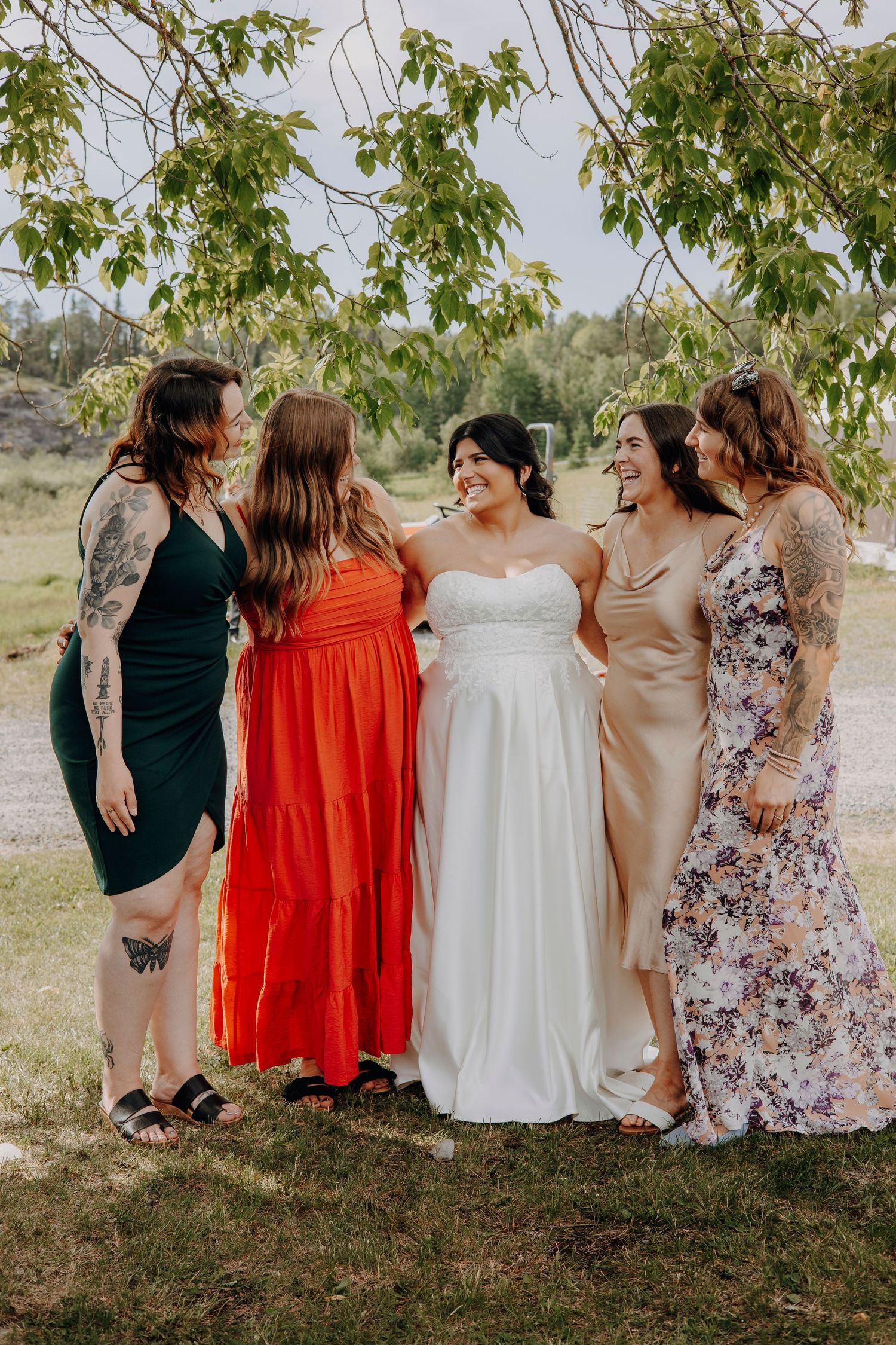 A group of bridesmaids in colorful dresses standing together outdoors.