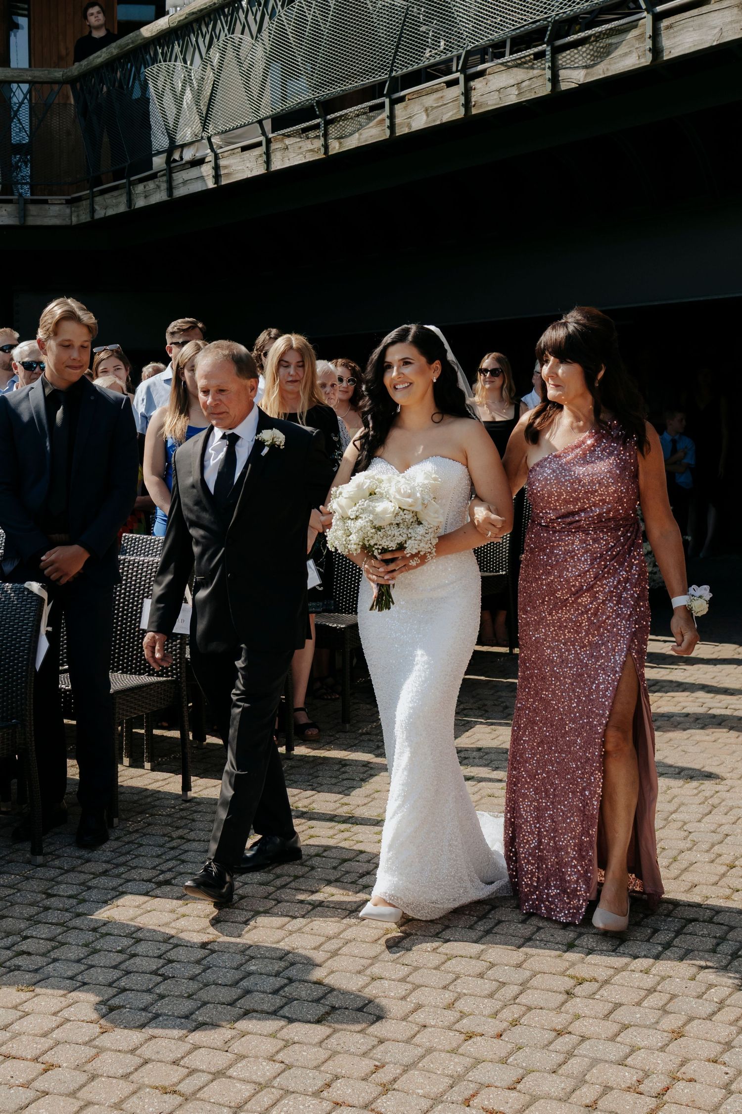 Wedding party lined up on cobblestone pavement outside venue.