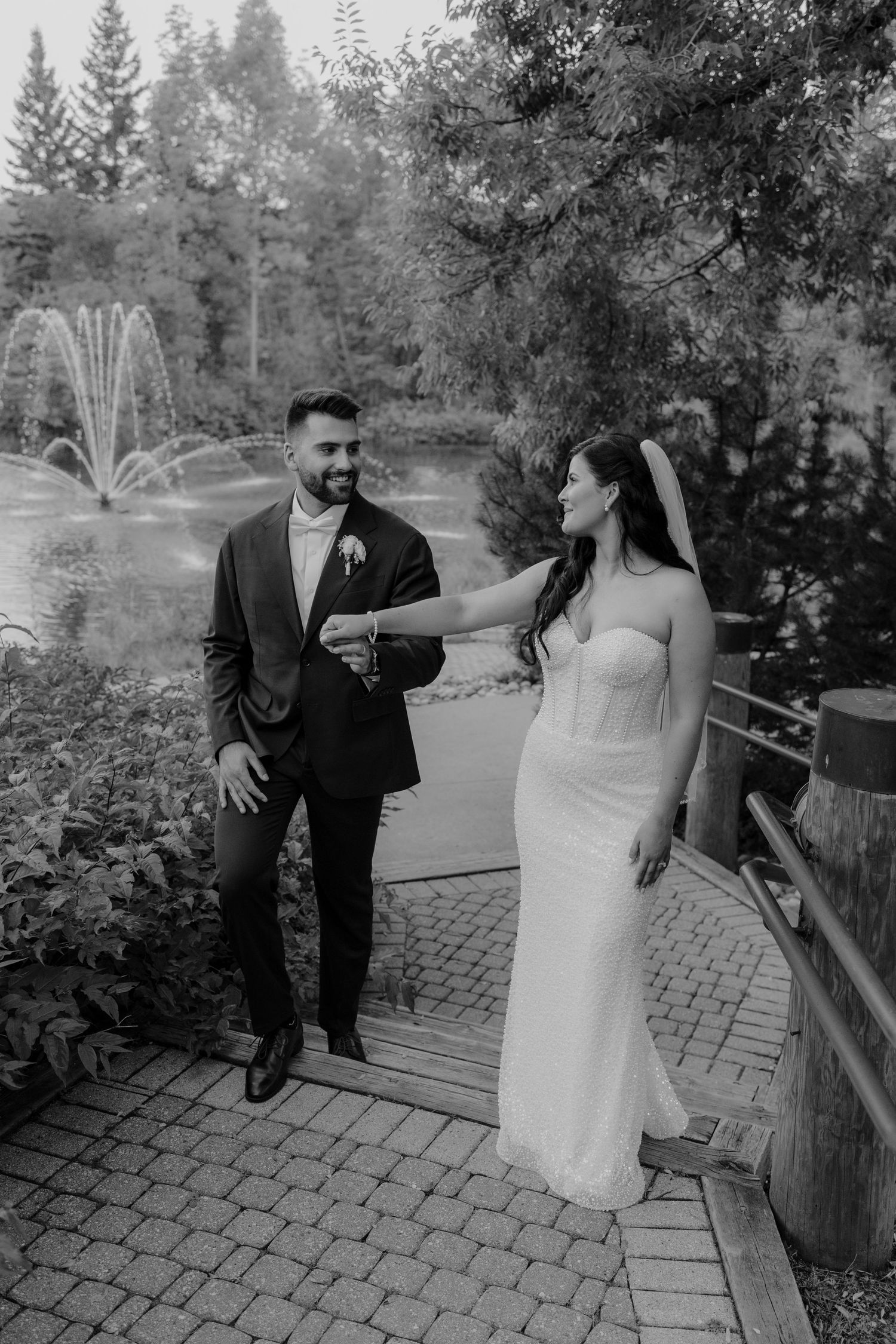 Wedding couple shares playful moments on a brick patio surrounded by greenery.