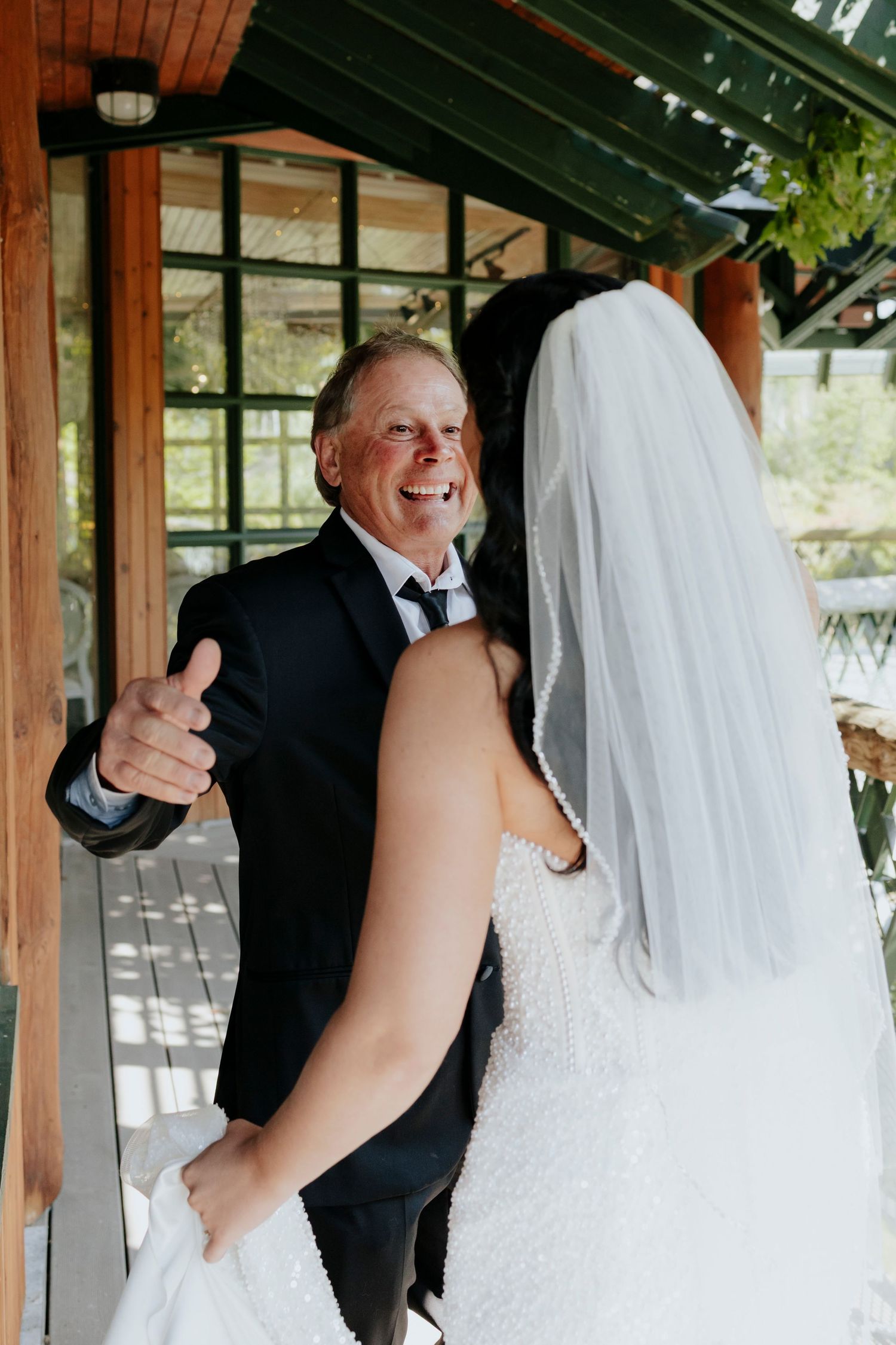 Emotional first look moment under a wooden pavilion at a wedding venue.