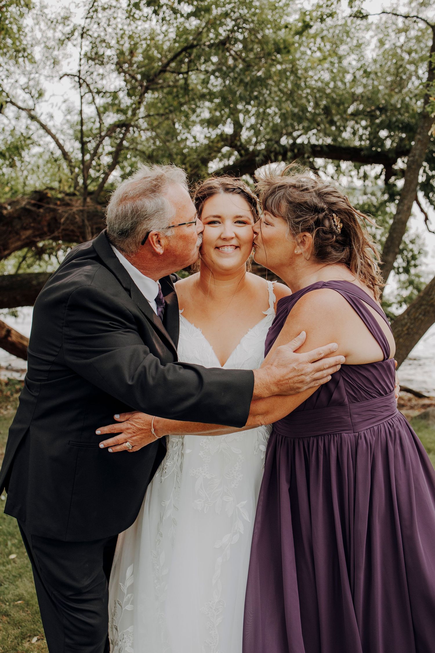 Joyful wedding party shares emotional embraces during outdoor celebration.