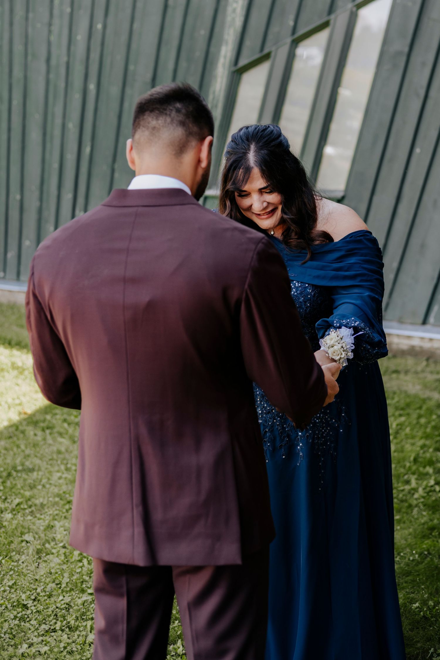 Wedding party members in burgundy suits and navy dresses pose together outdoors.