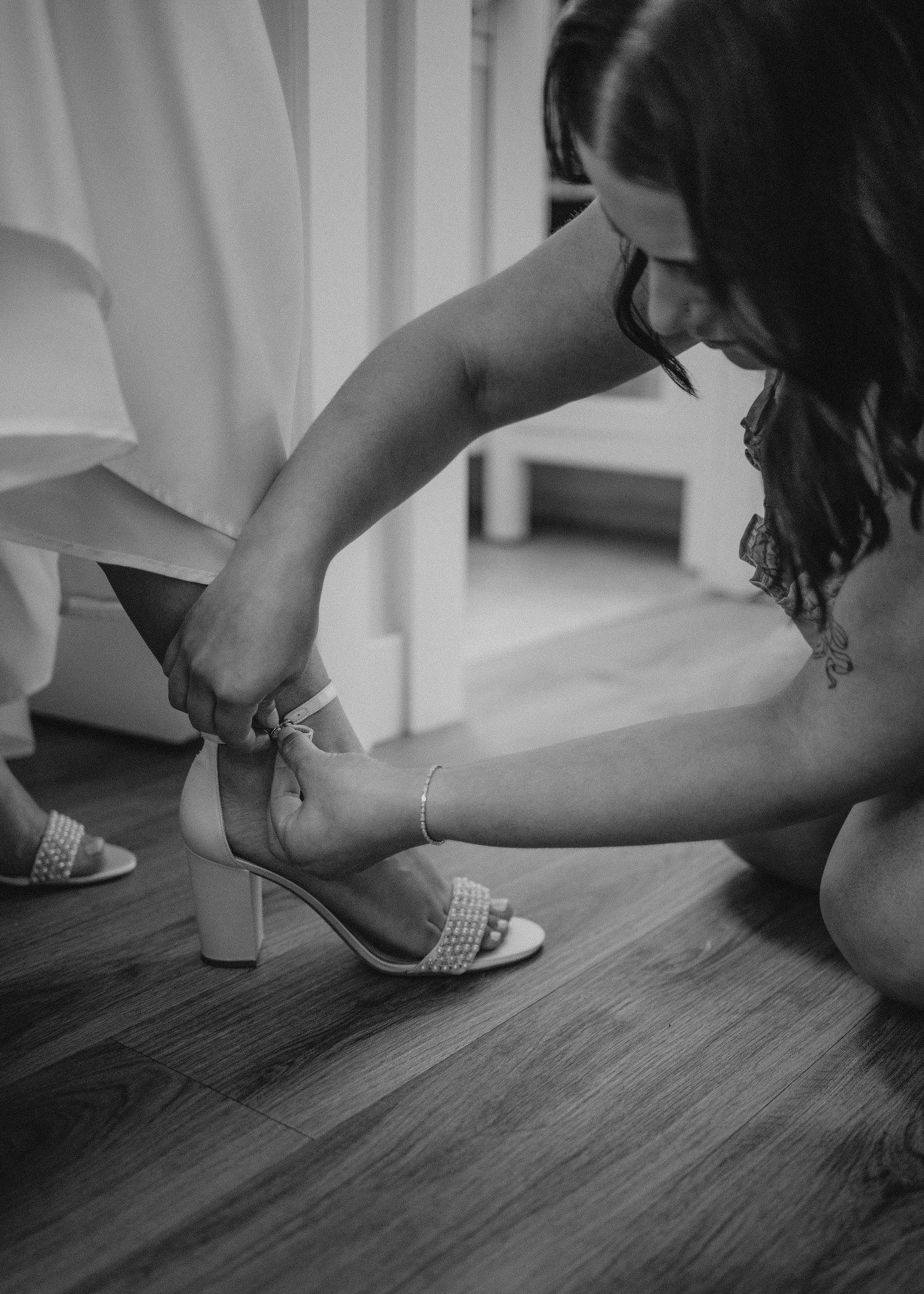 Black and white image of someone fastening formal shoes.