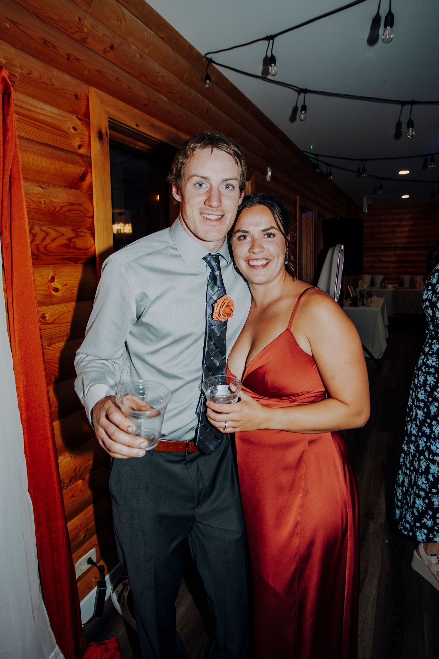 Wedding guests enjoying drinks and celebrations inside rustic log cabin venue.