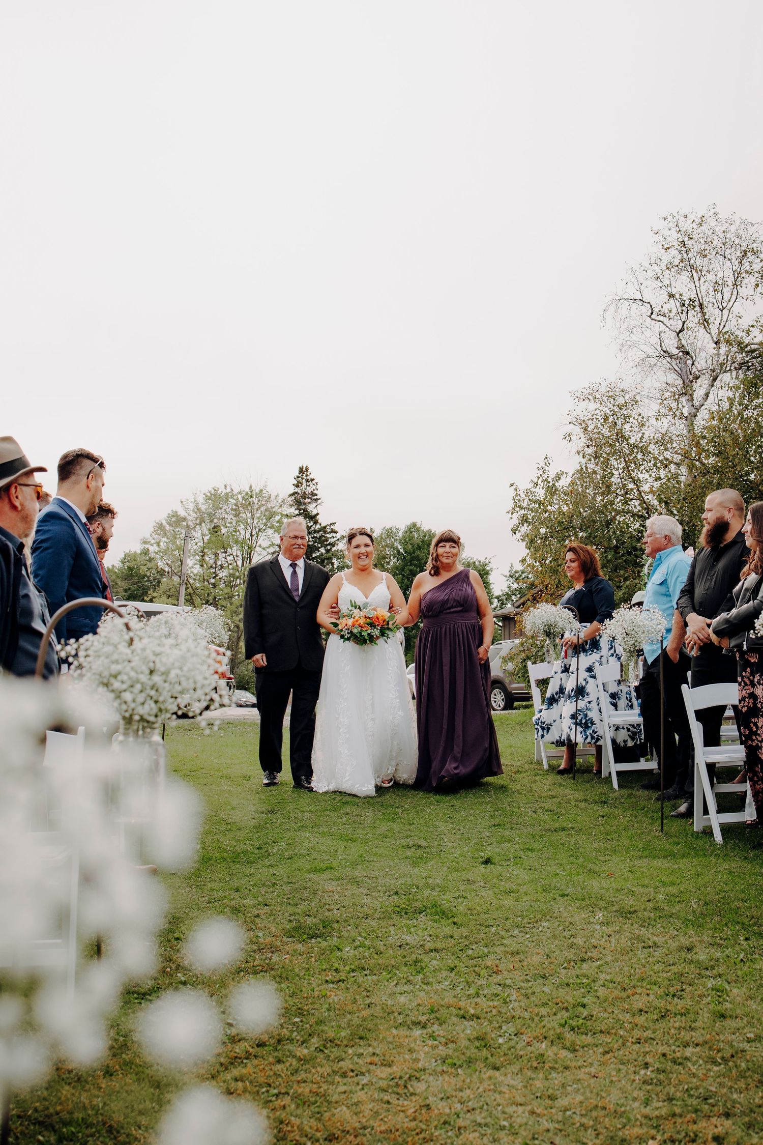 Outdoor wedding ceremony setup with white chairs on a grassy lawn.