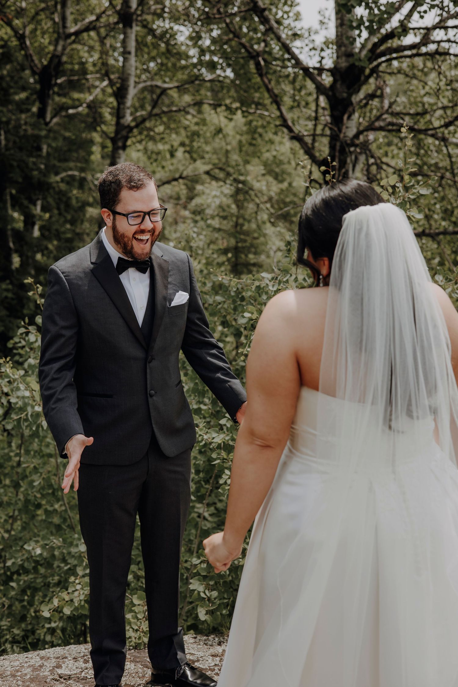 A touching first look moment between a bride and groom in a wooded outdoor setting during their wedding day.